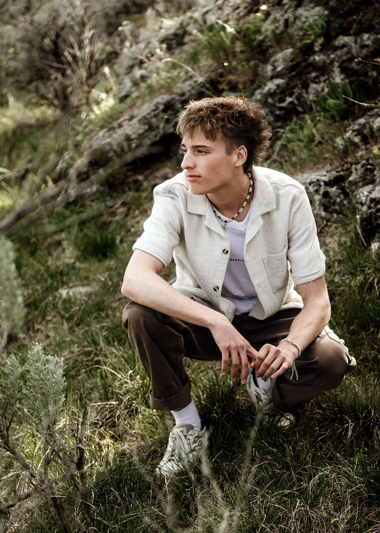Senior boy sitting in mountains looking off into distance