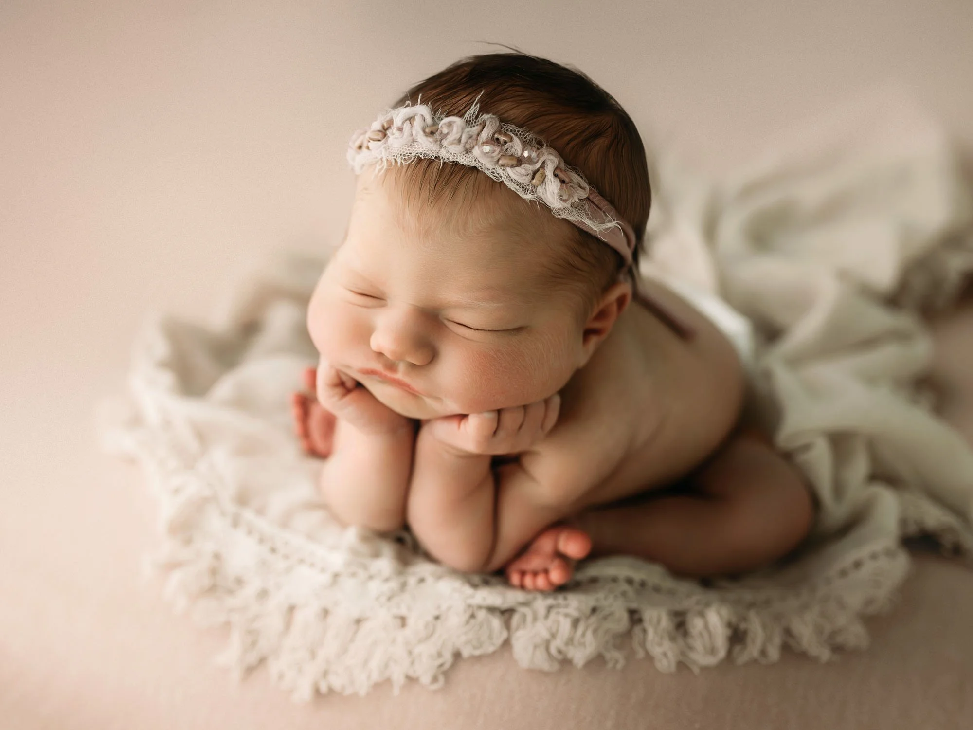 Newborn in classic froggy pose on neutral studio backdrop