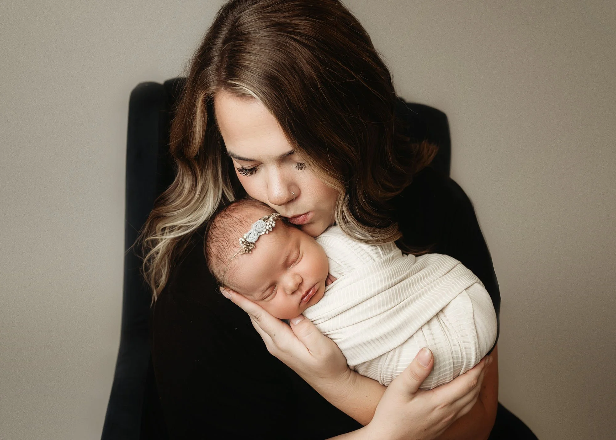 mama kissing baby wrapped in swaddle