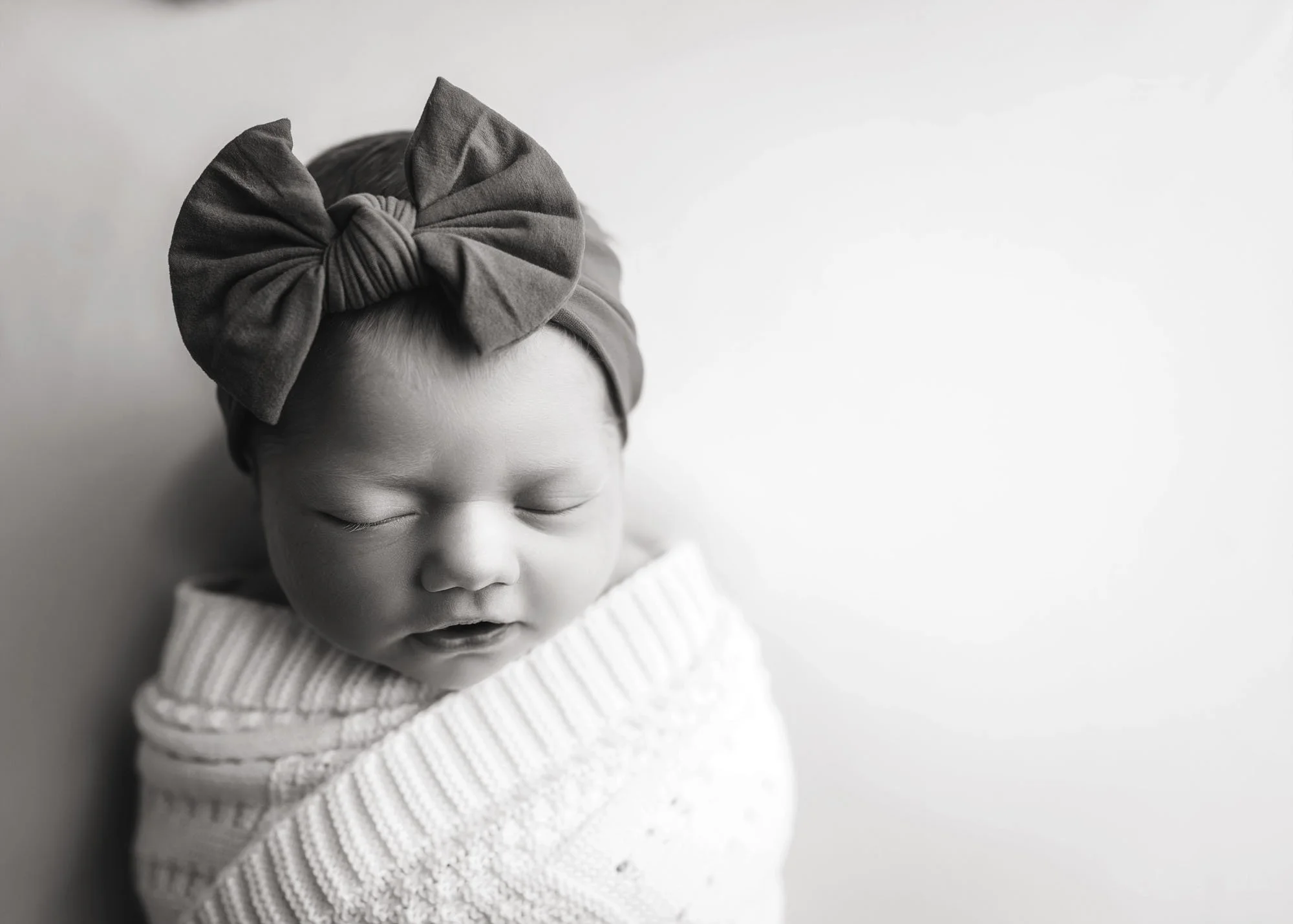 Black and white newborn portrait with soft negative space