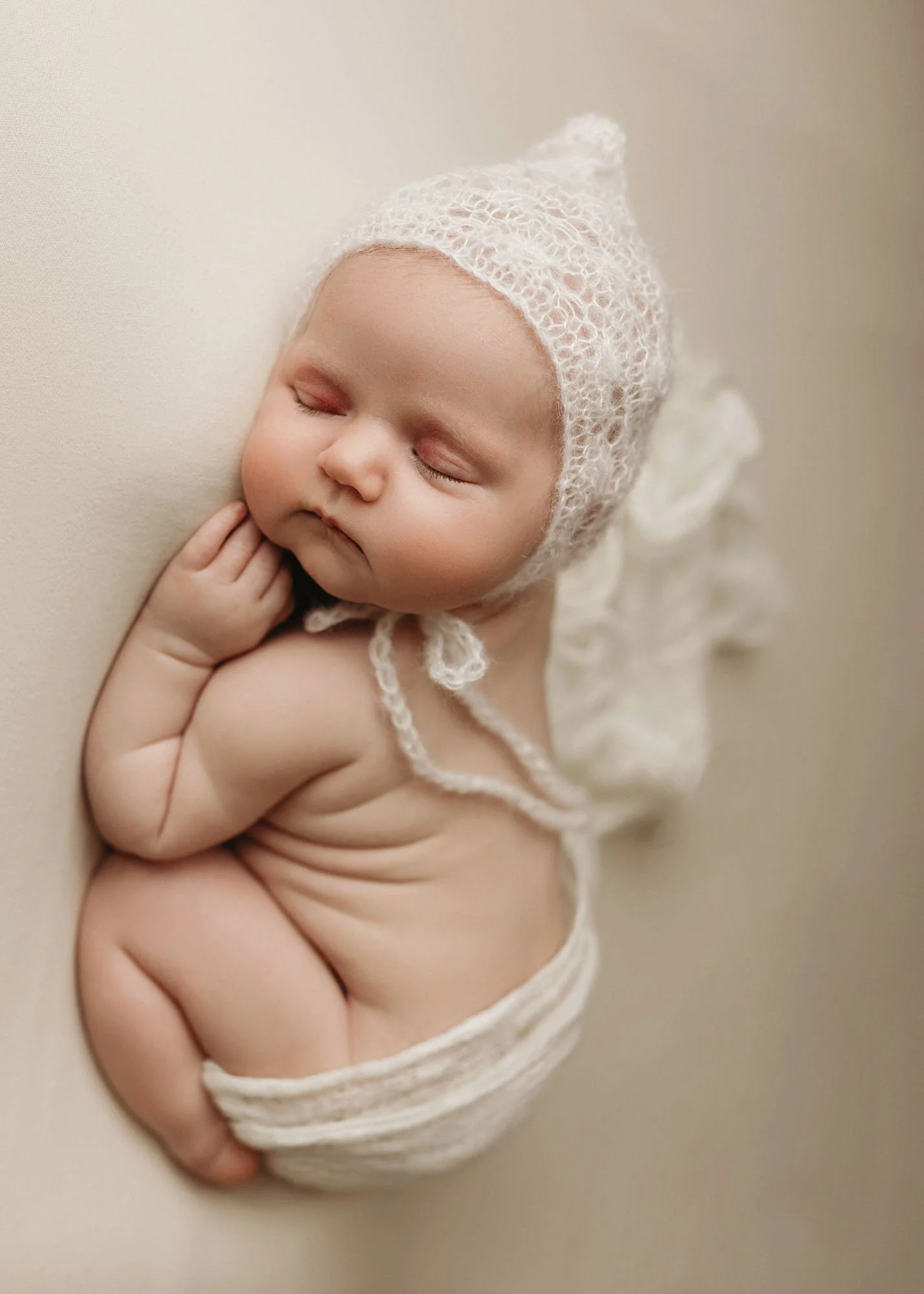 Newborn in neutral bum up pose with textured wrap and knit hat