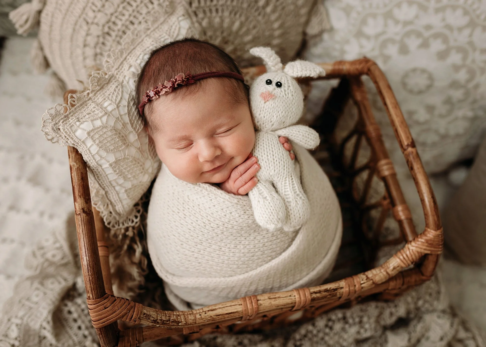 baby holding bunny in wood cradle with a smile