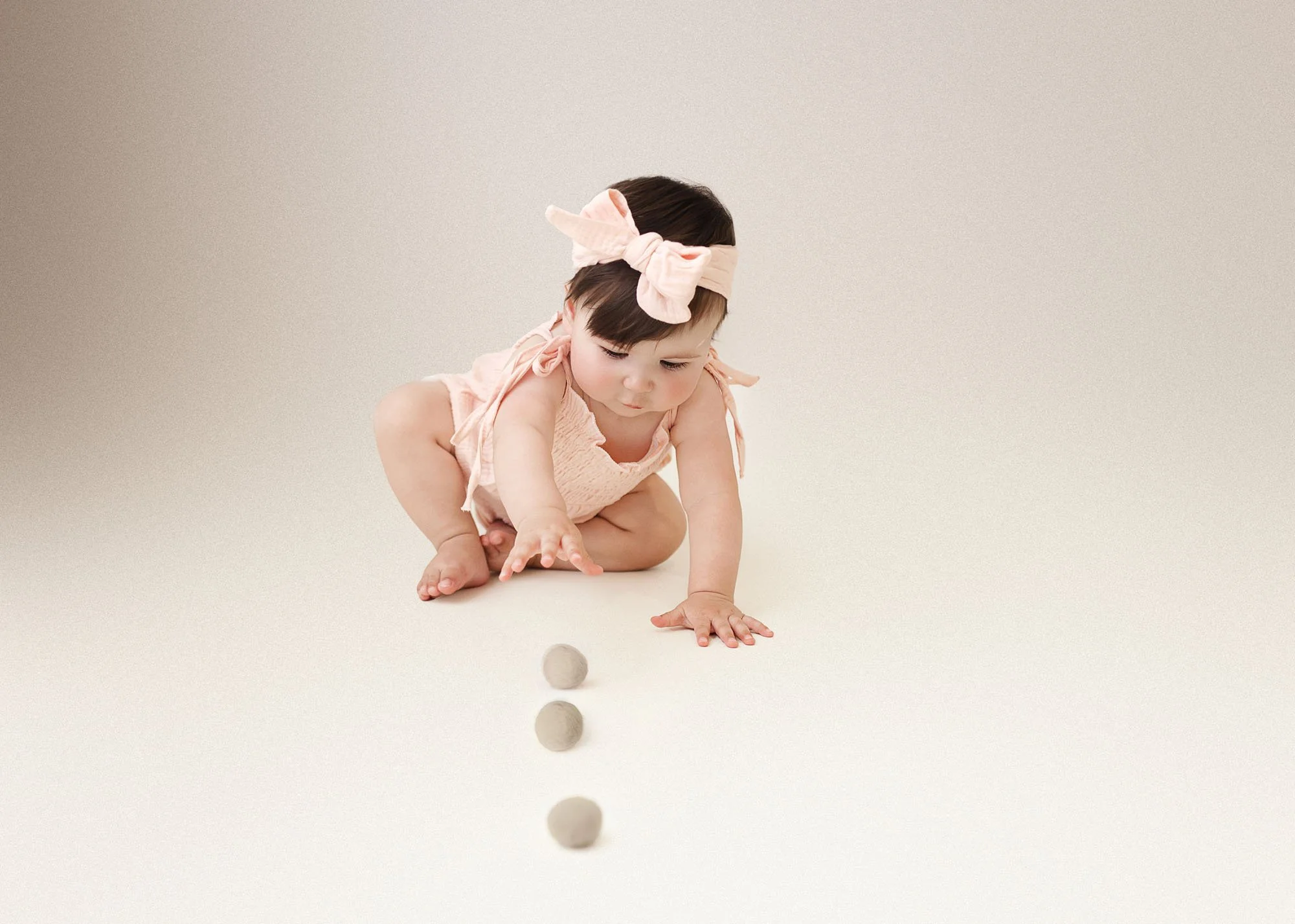 Baby in studio milestone session with playful expression