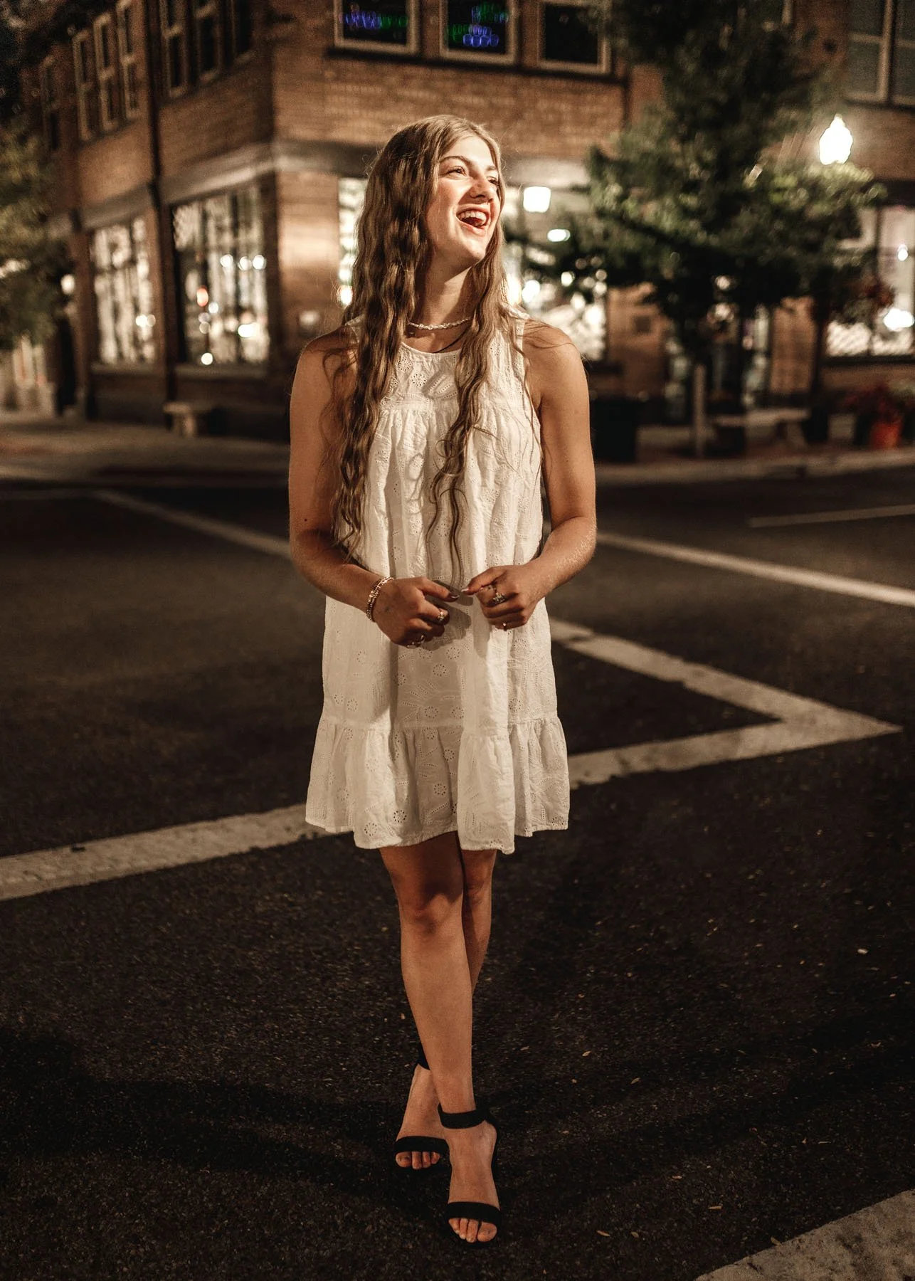 Senior girl in white dress standing at night crossroads looking off