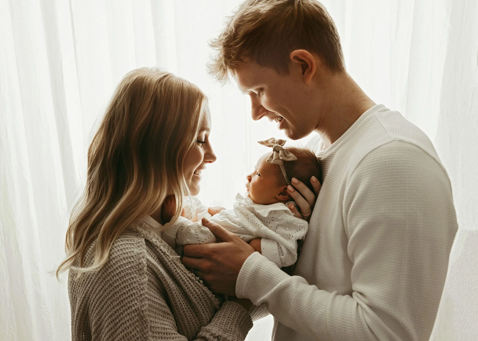 backlit family mama and daddy looking at baby