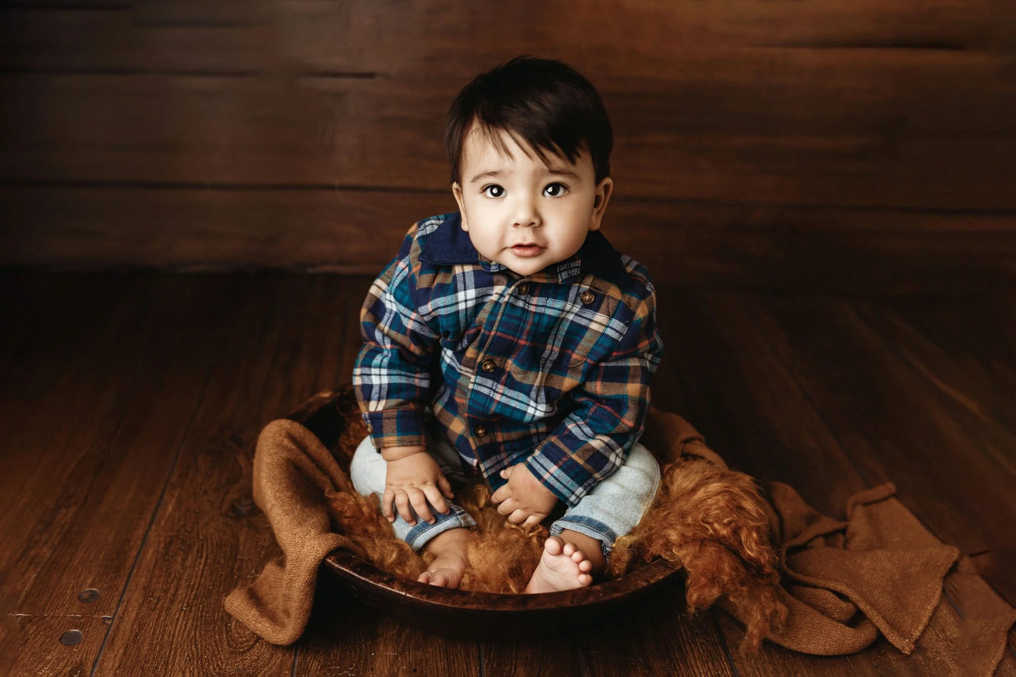 Infant posing in rustic bowl with neutral studio backdrop