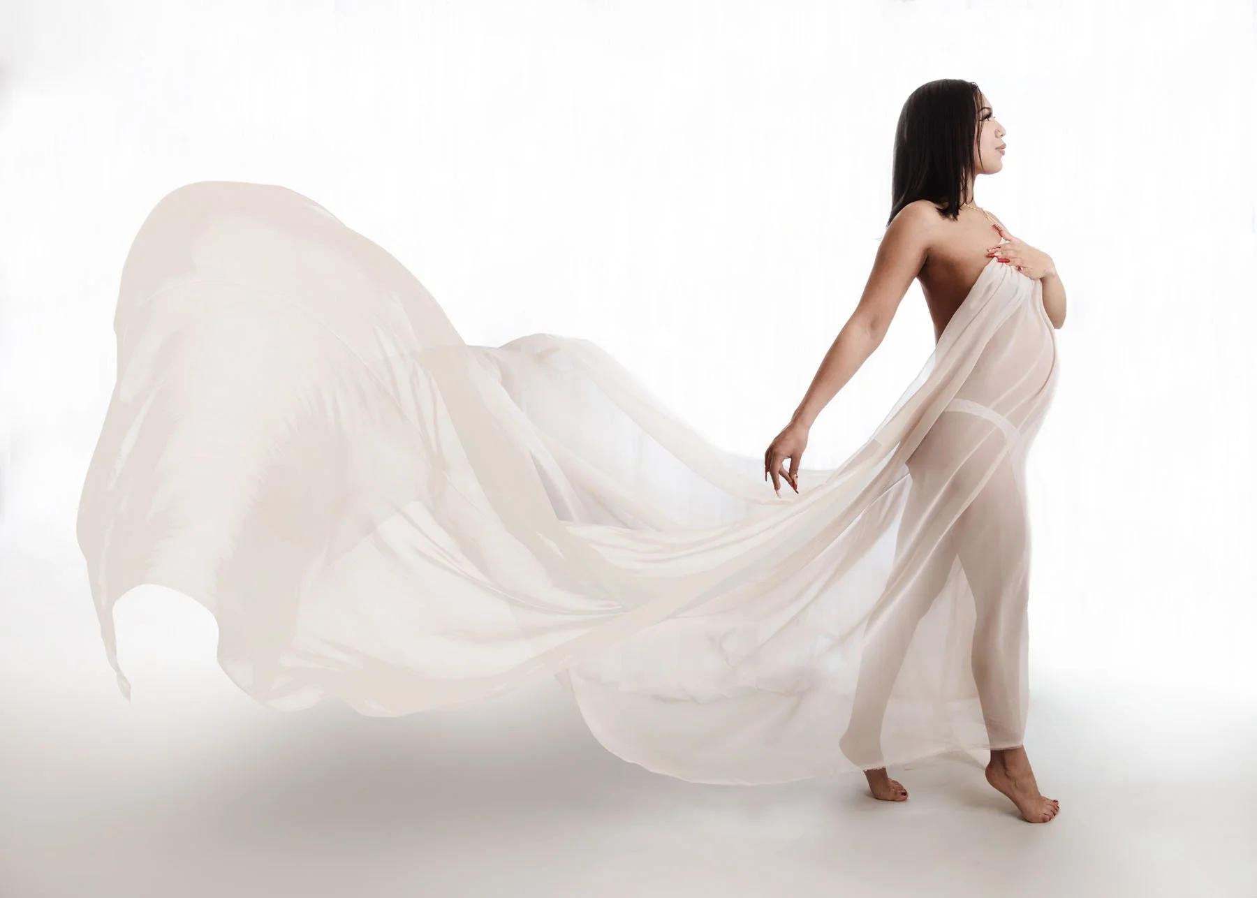 Expecting mama in soft pink flowy dress showing side profile of pregnant tummy