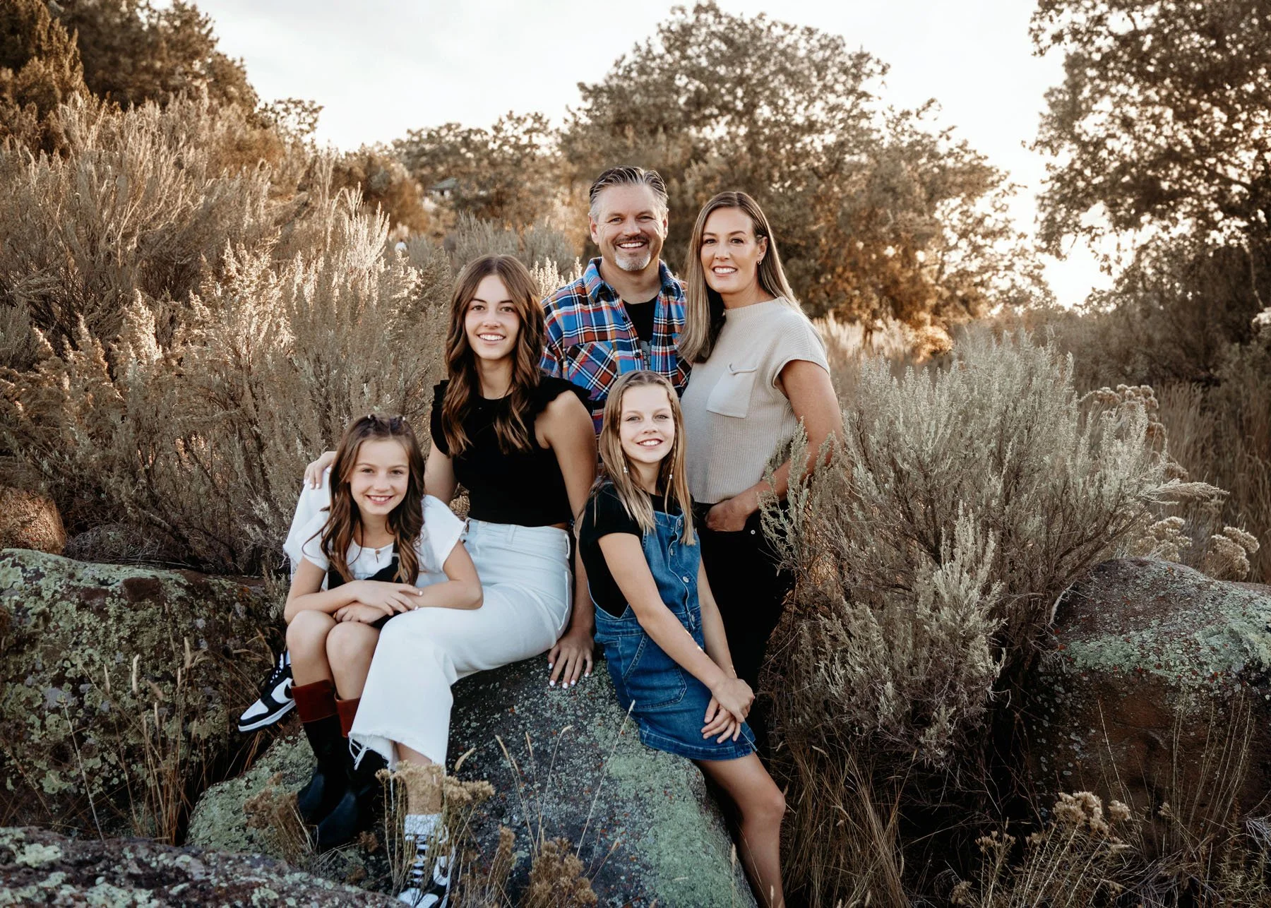 Family posing on rocks with sagebrush and river in Idaho Falls