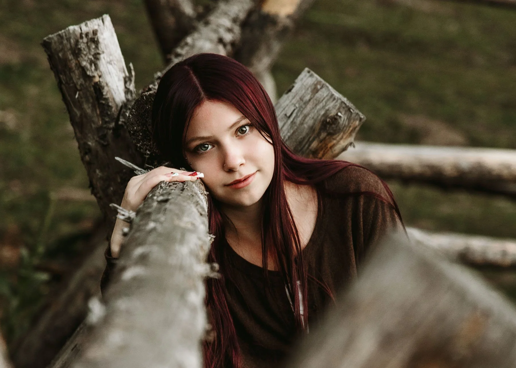 Senior girl leaning on fence, serious expression in outdoor session