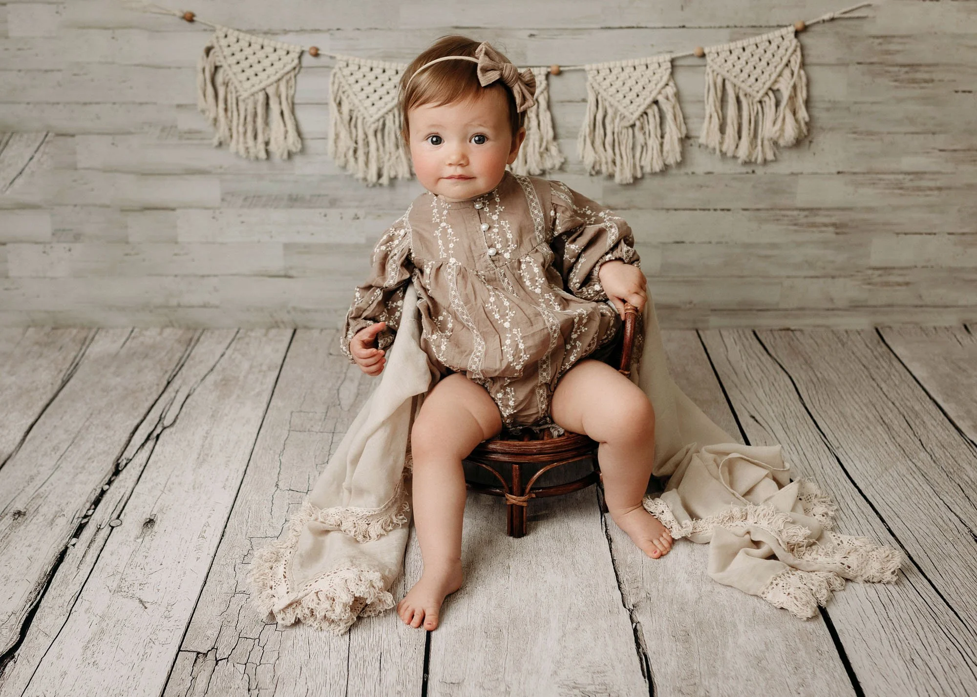 Infant posing naturally on rustic wooden chair in studio