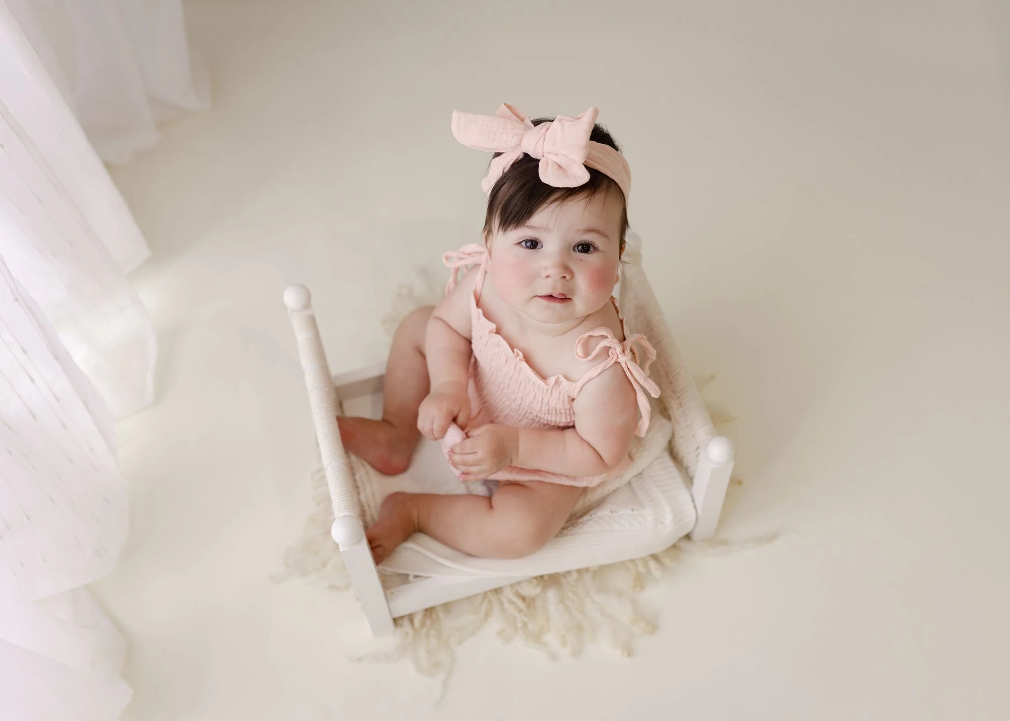 Studio milestone session with baby in miniature bed