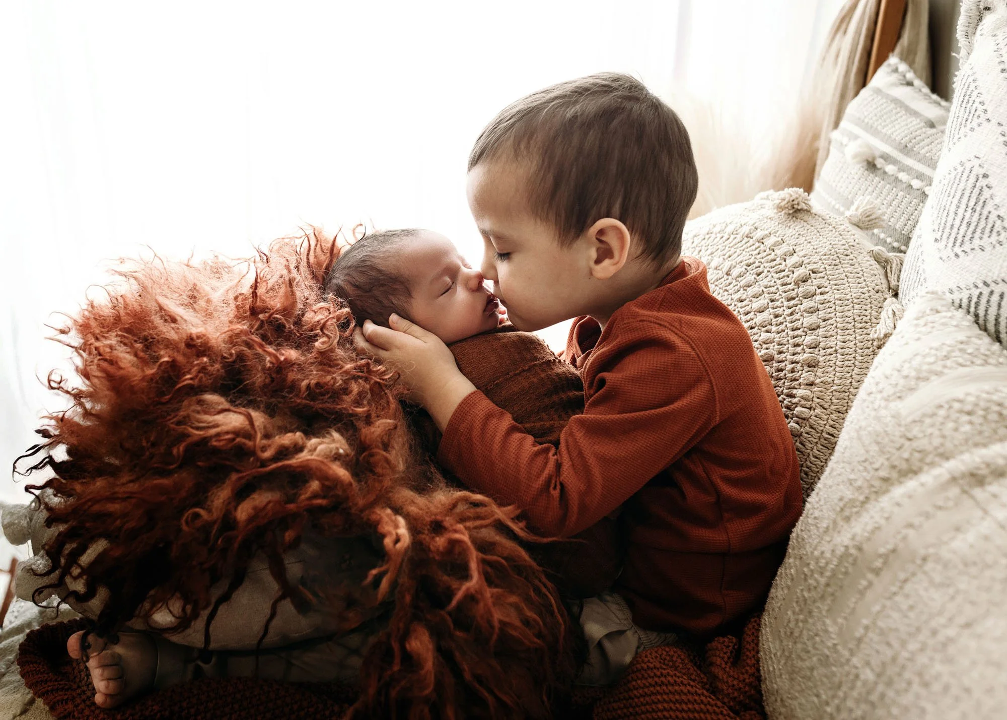 big brother kissing newborn brother