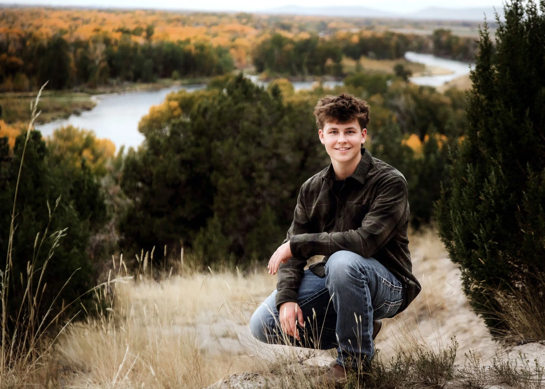 Four senior boys in plaid shirts posing on mountain with river below