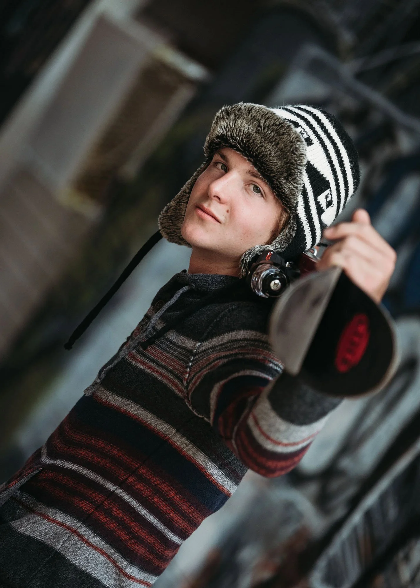 Teen boy with snowboard over shoulders looking at camera seriously