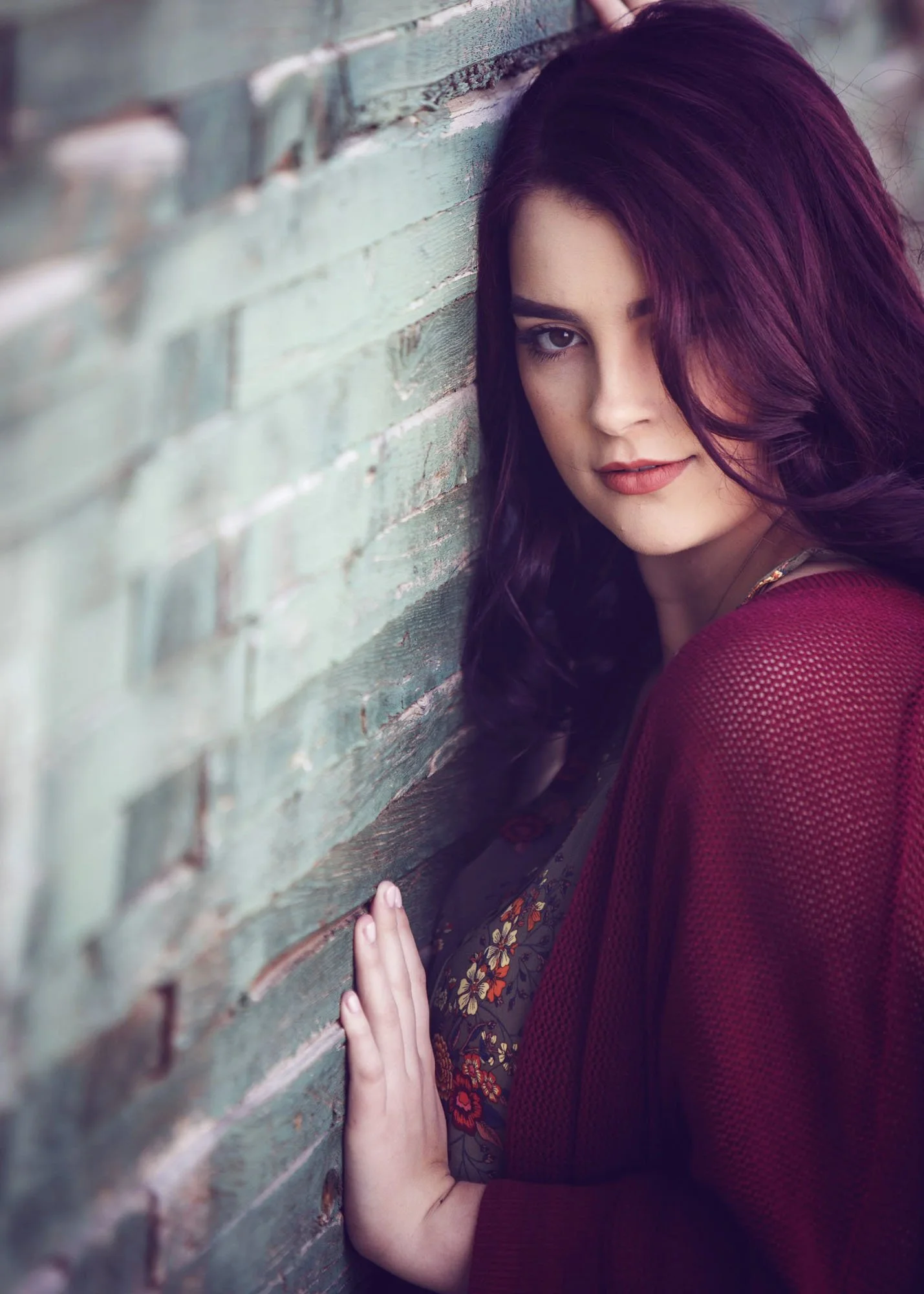  Teen girl leaning against green wall, head turned towards camera