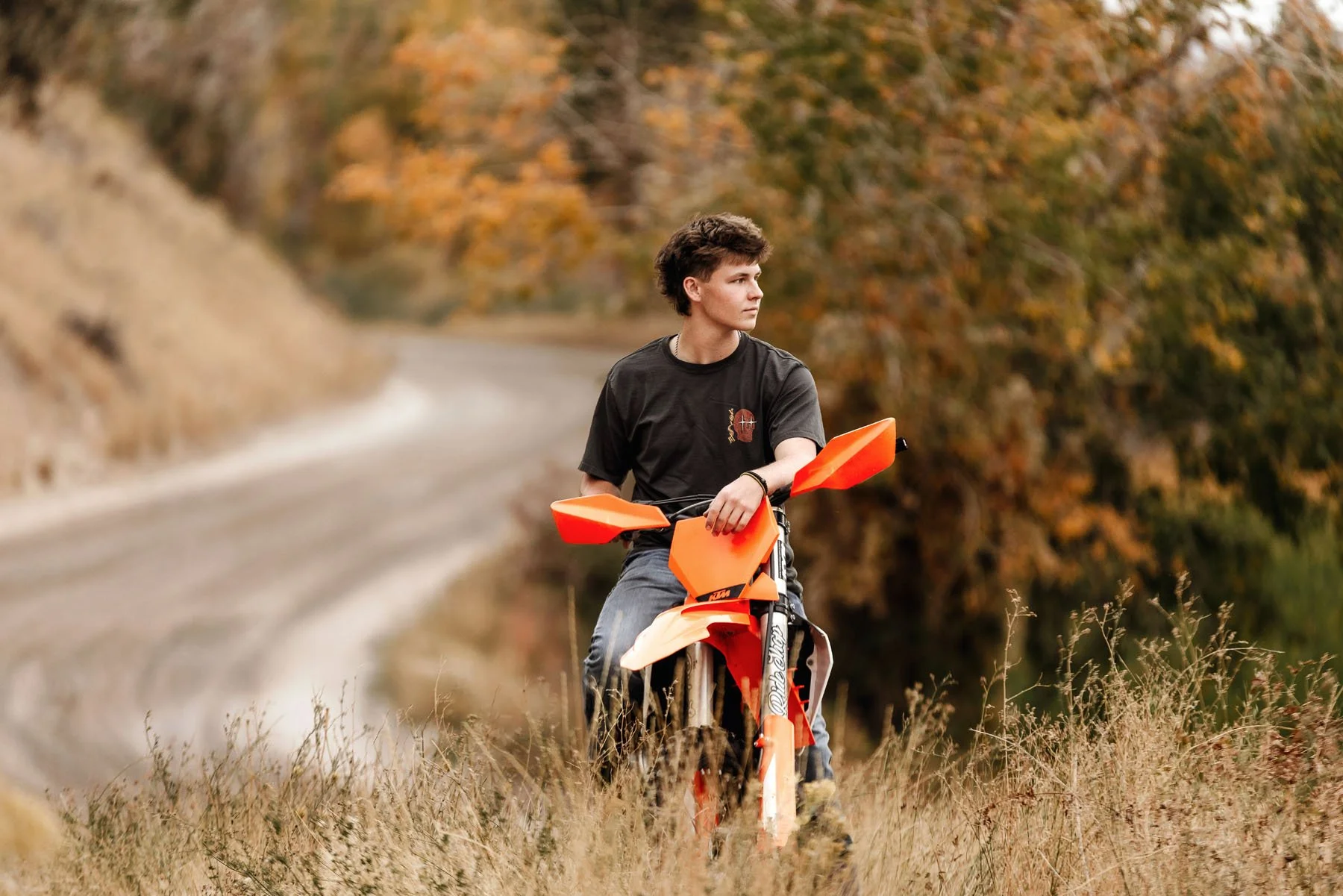 Senior boy on dirt bike with curvy mountain road and fall foliage