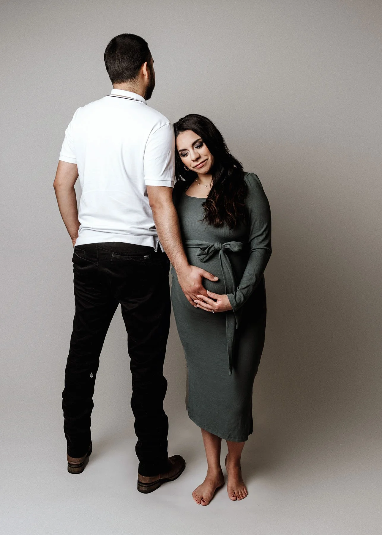 Daddy facing backwards, mama holding him, baby bump visible, baby facing forward