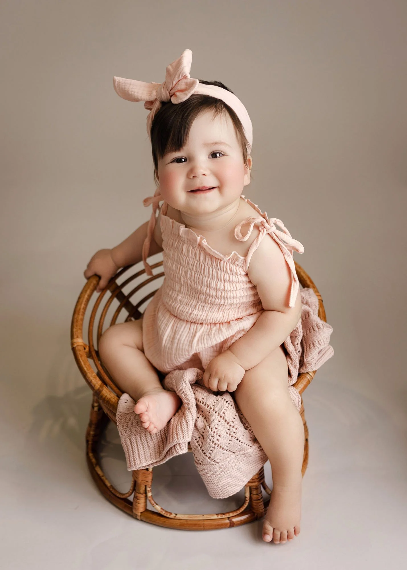 Studio milestone session with baby on chair in front of bed