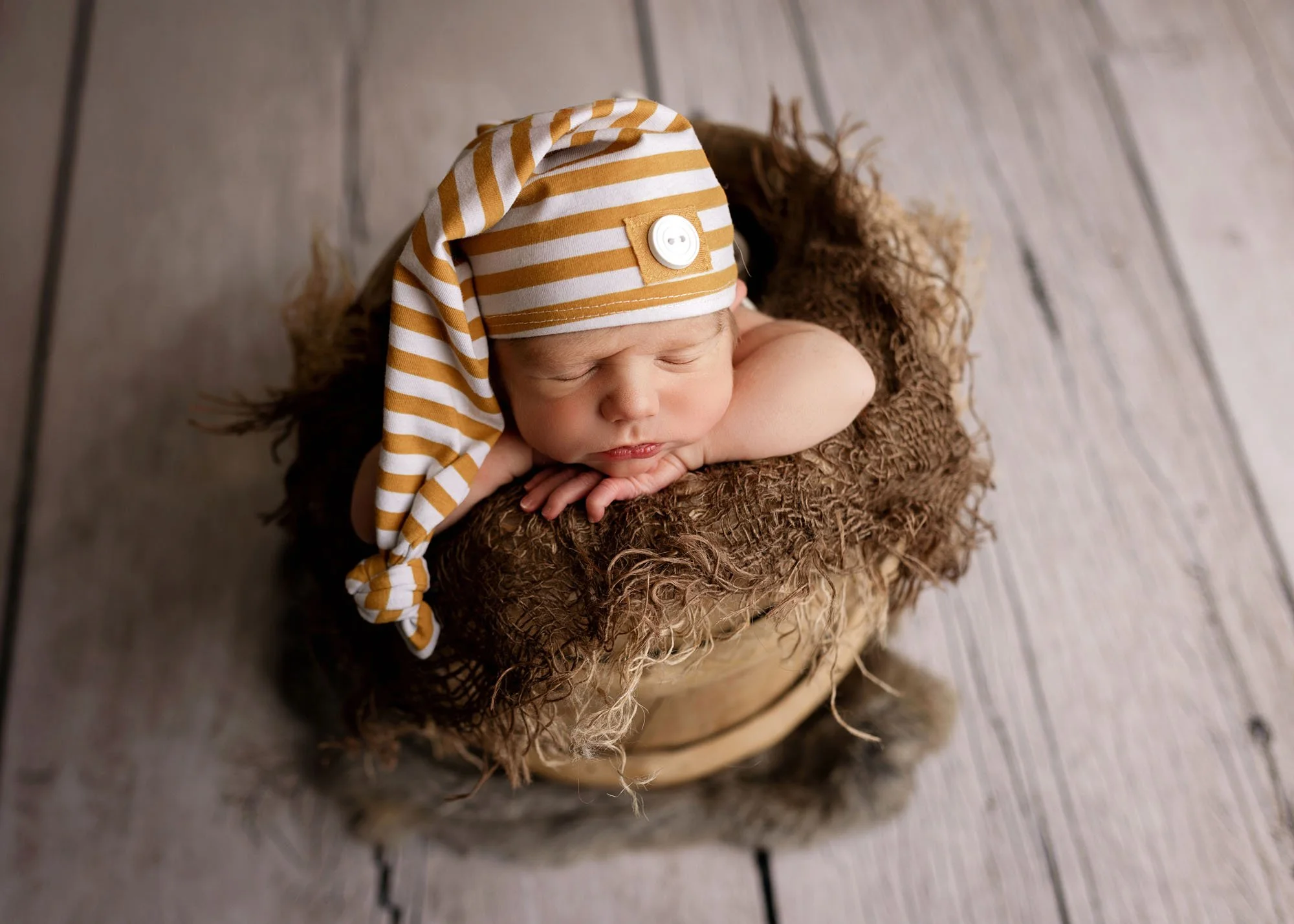 baby with striped sleepy hat in bucket pose