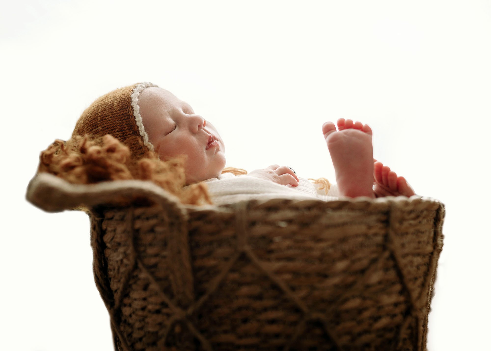 Backlit profile portrait of newborn posed in bucket prop
