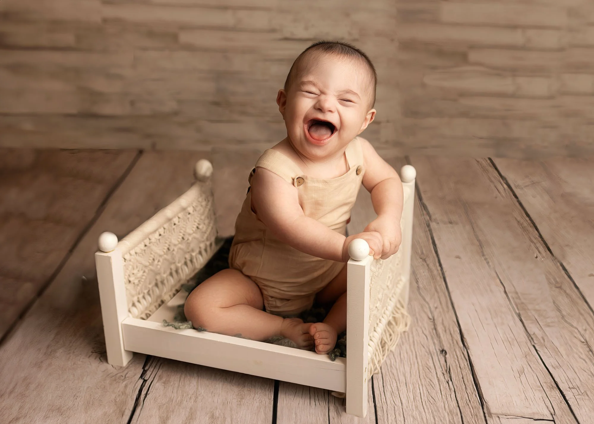 Baby sitting and playing in child-size bed