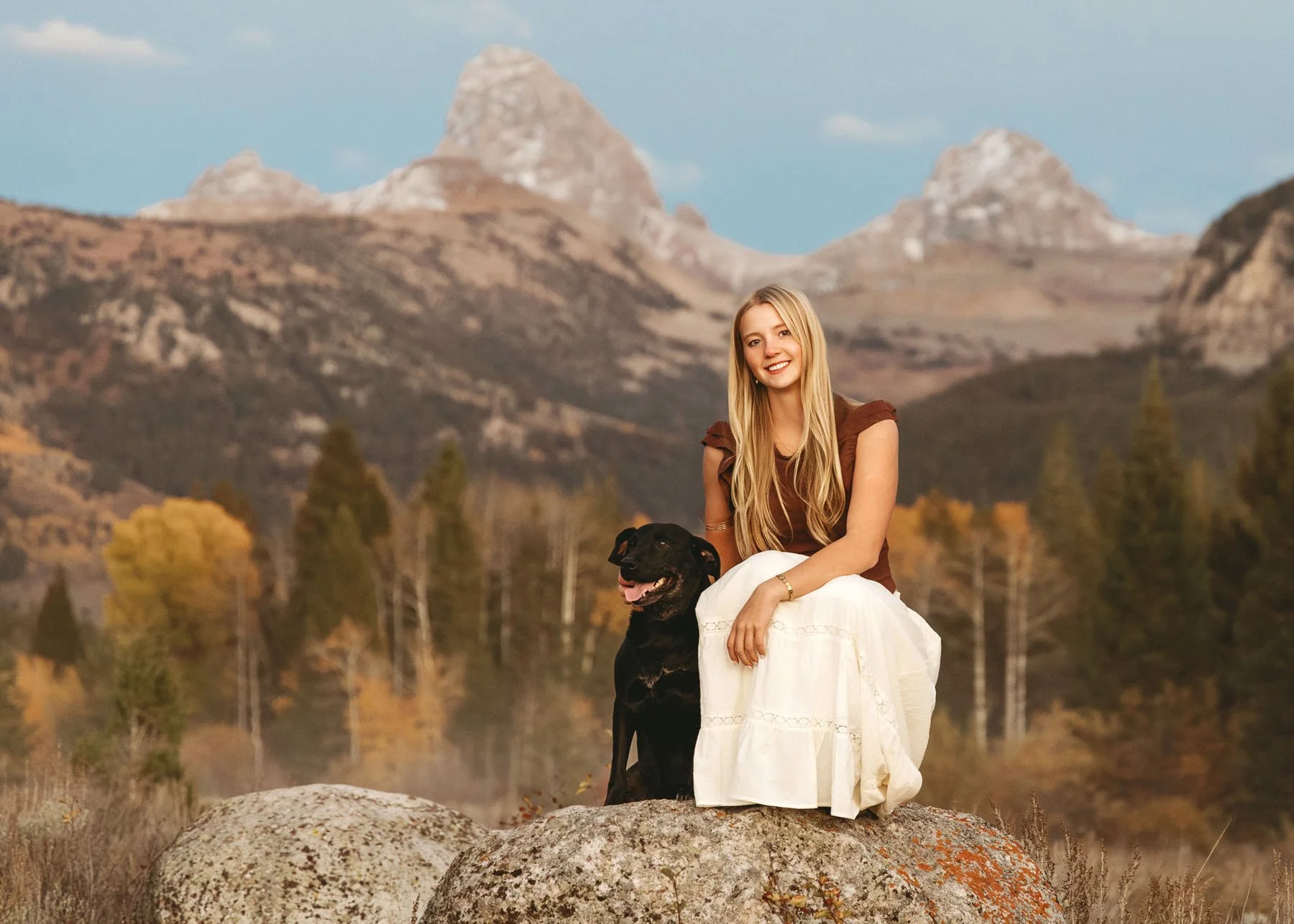 Two senior girls posing with Grand Teton Mountains behind, one with dog