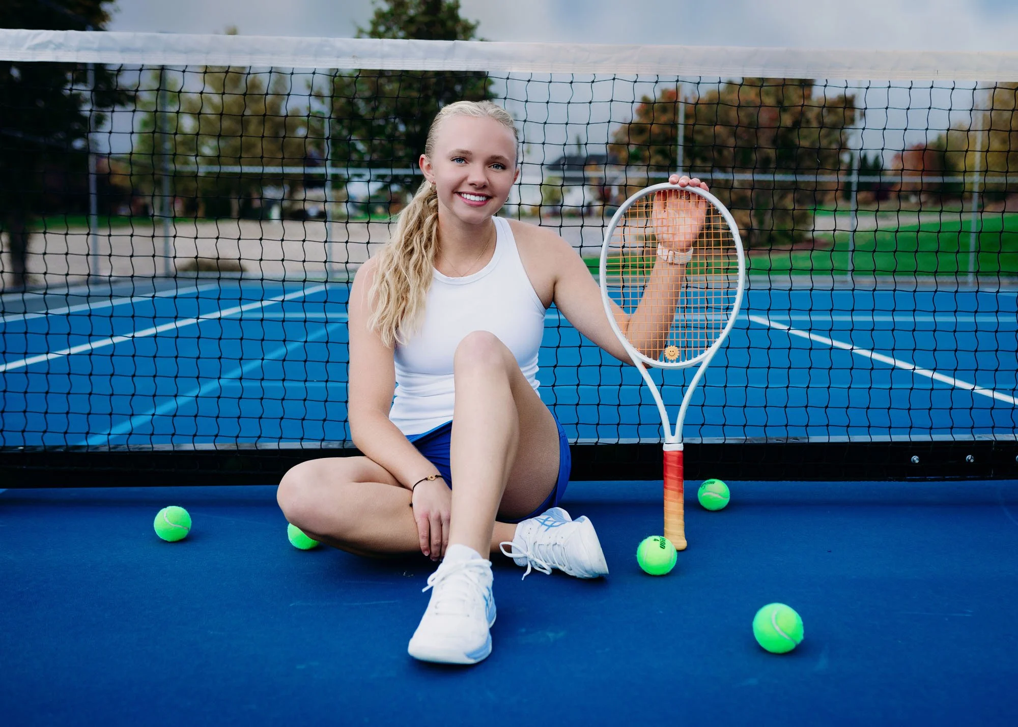 Teen girl holding tennis racket for outdoor senior session