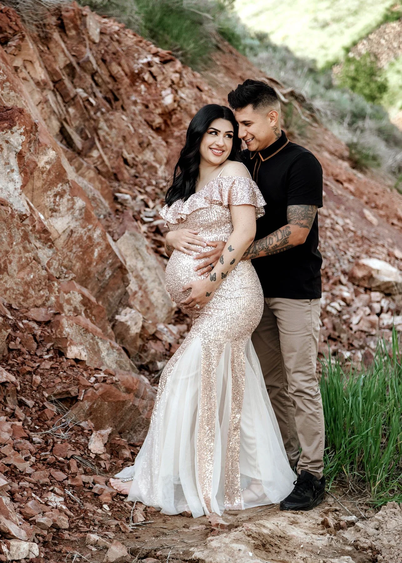 Three couple poses in front of red rocks holding baby bumps