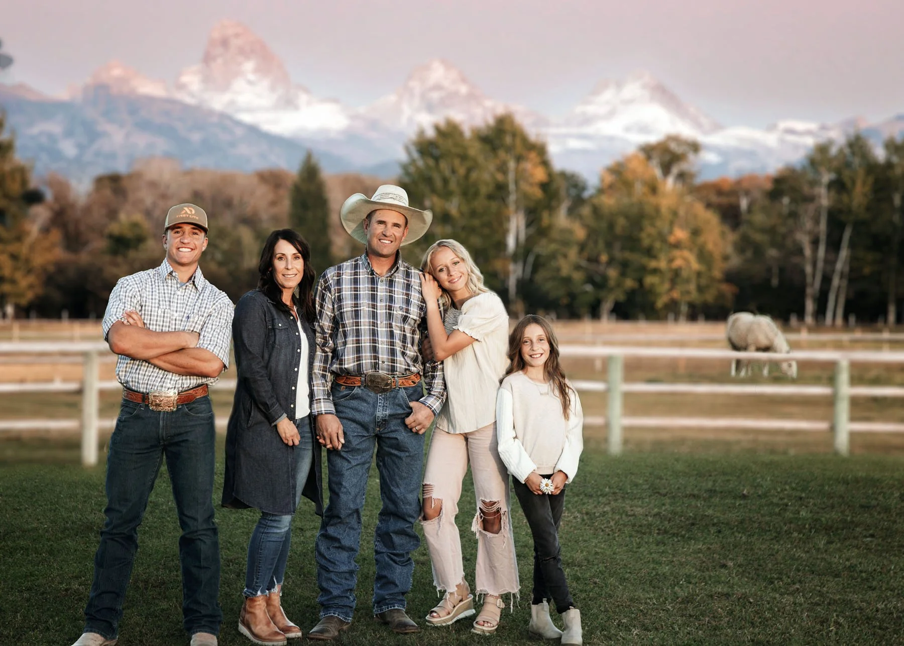 Family with horses posing in pasture with Teton Mountains
