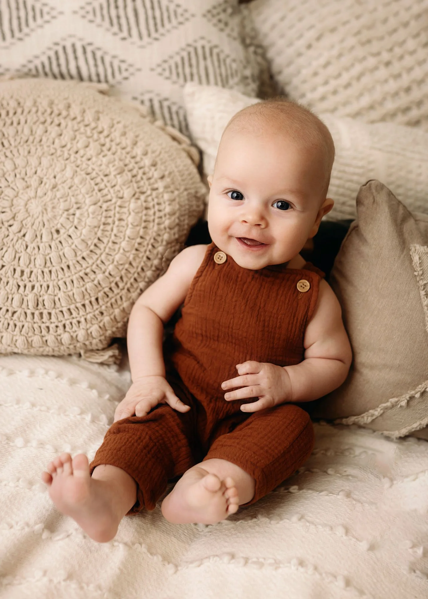 Baby sitting on bed for indoor milestone session