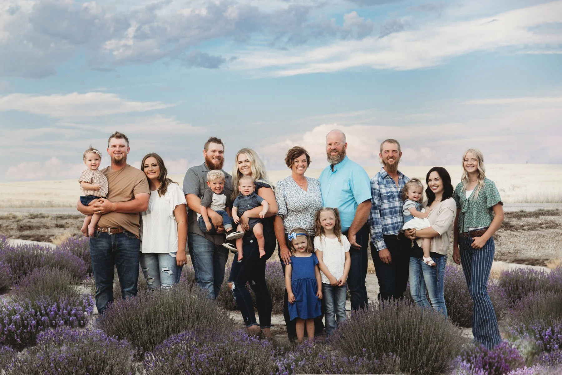 Family posing in lavender field under bright blue sky