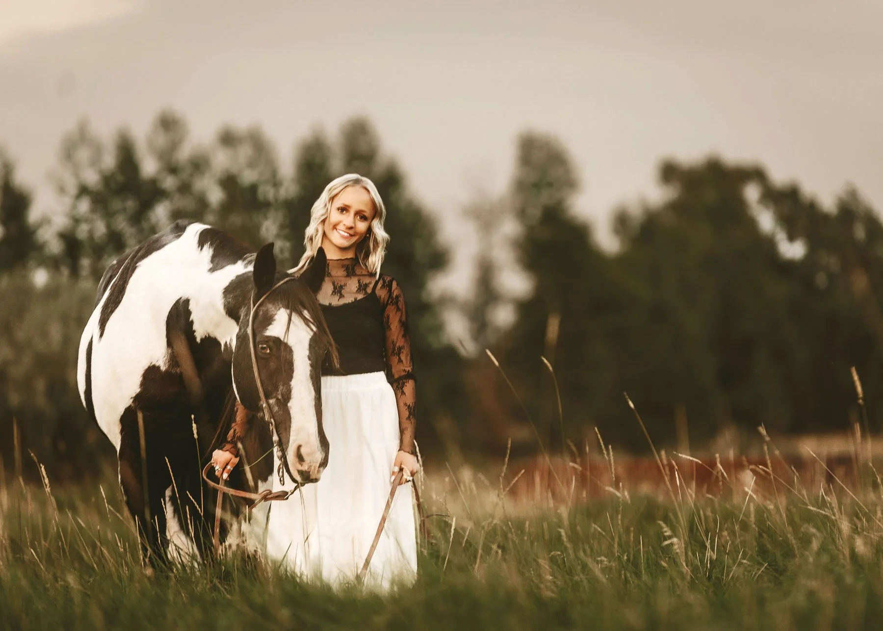 Senior girl walking outdoors with horses during golden hour