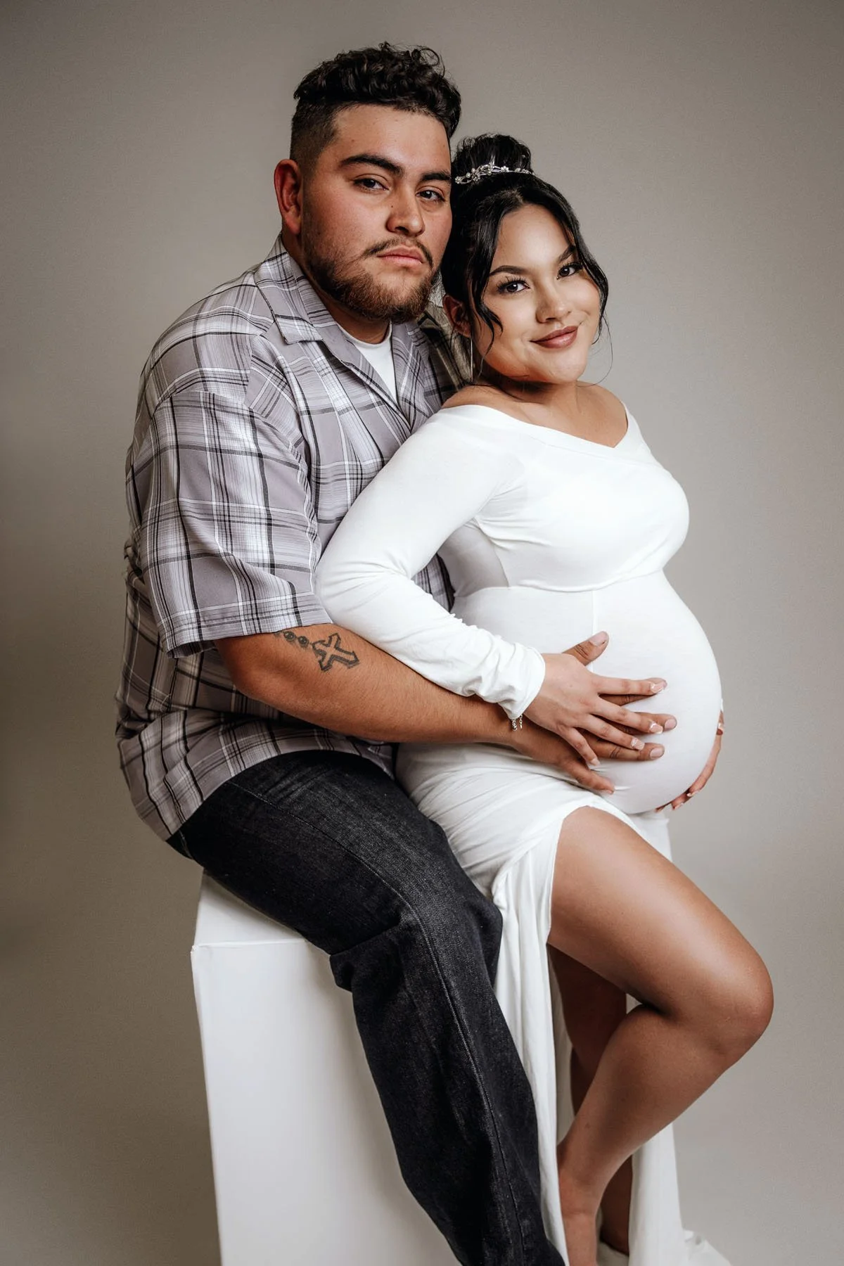 Daddy sitting on chair, mama between legs holding baby bump