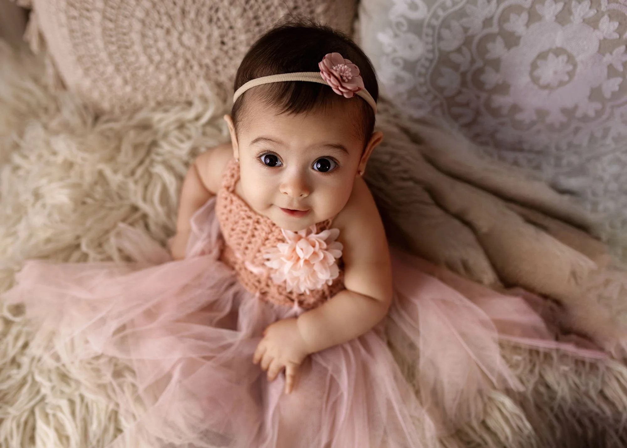 Milestone photography with baby sitting on bed