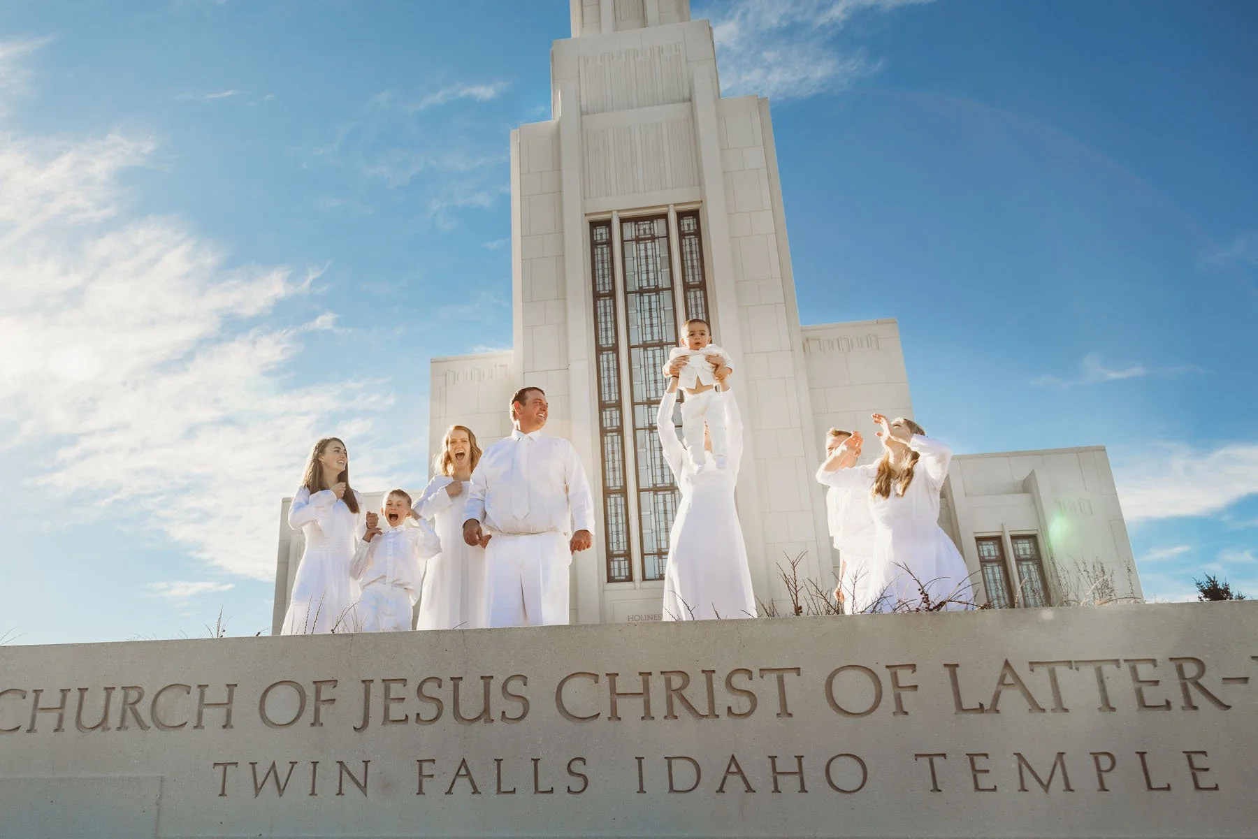 Family celebrating adoption in front of LDS temple in white clothing