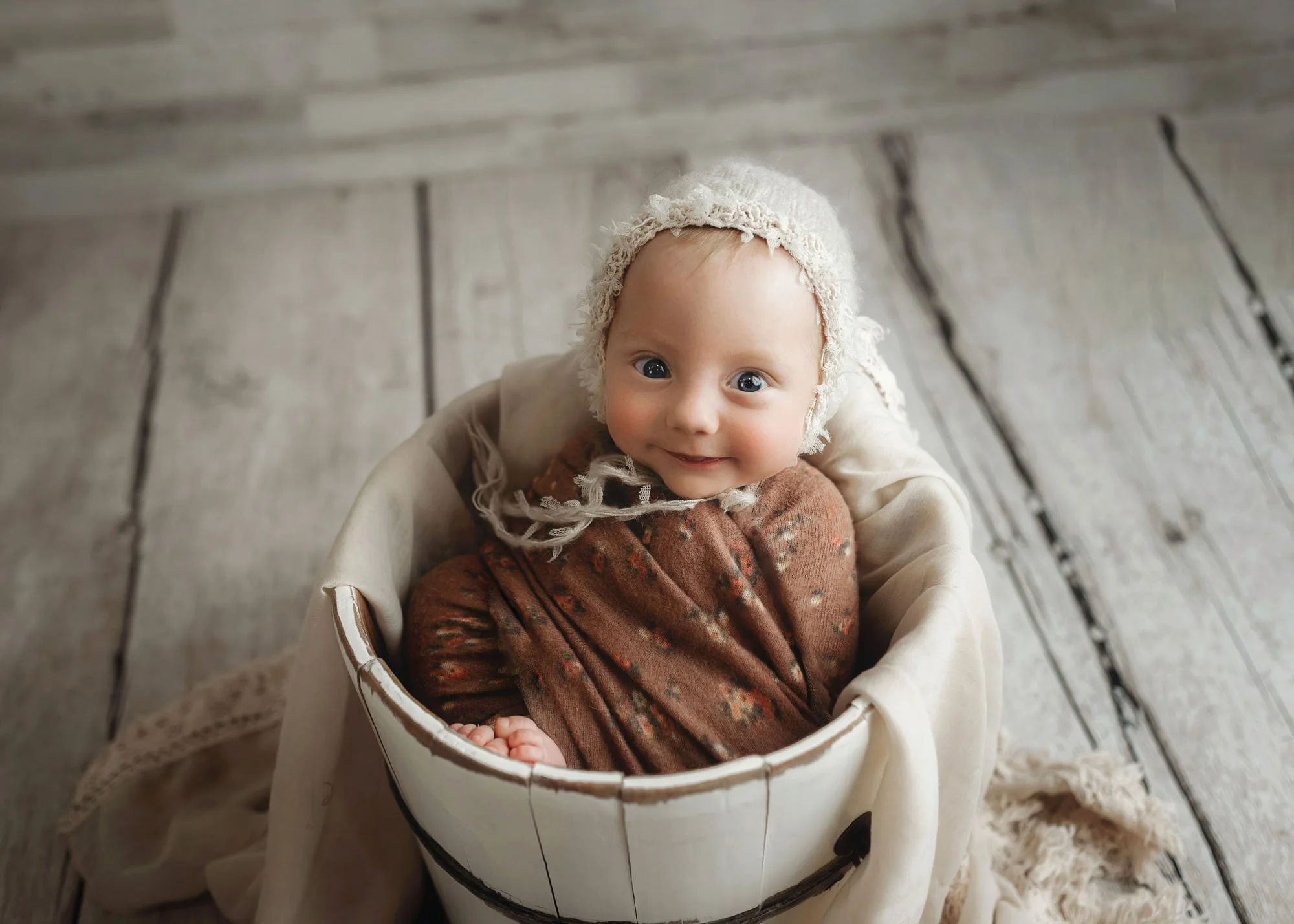 Baby sitting in bucket in studio milestone session
