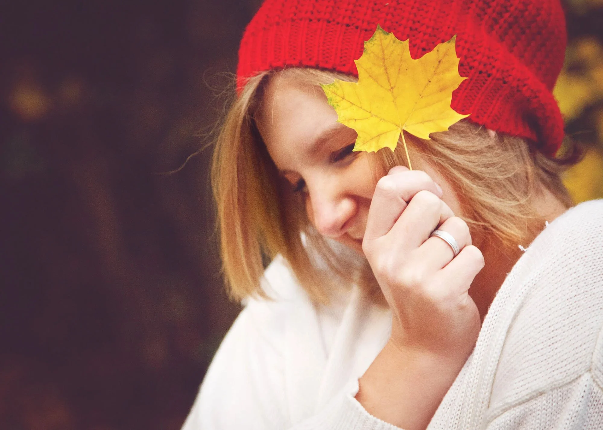 Teen girl in fall giggling holding yellow leaf in front of eye
