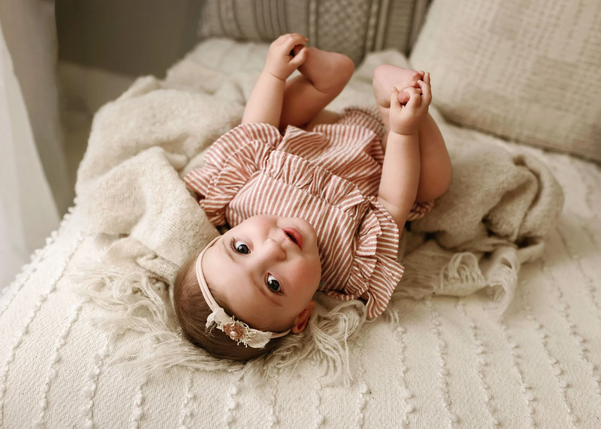 Baby lying on bed smiling during milestone session