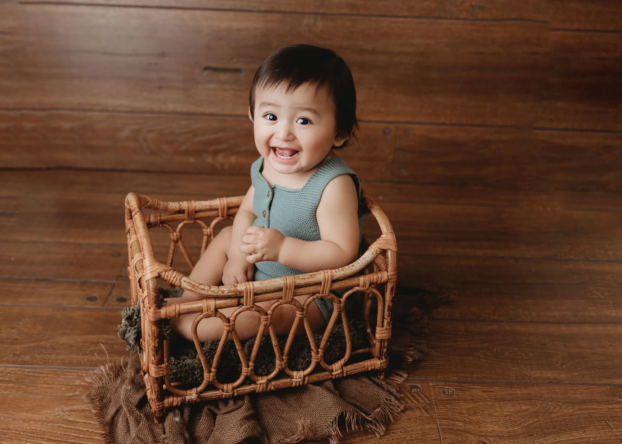 Infant milestone photography in wooden cradle