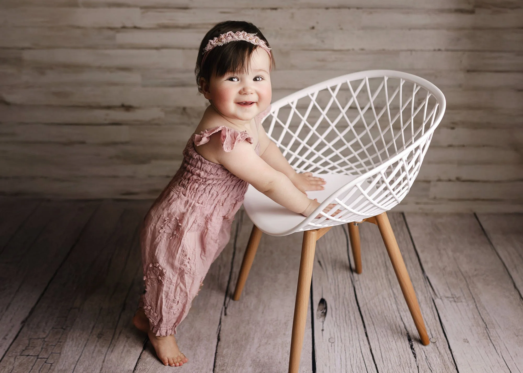 Infant posing on white chair for milestone session