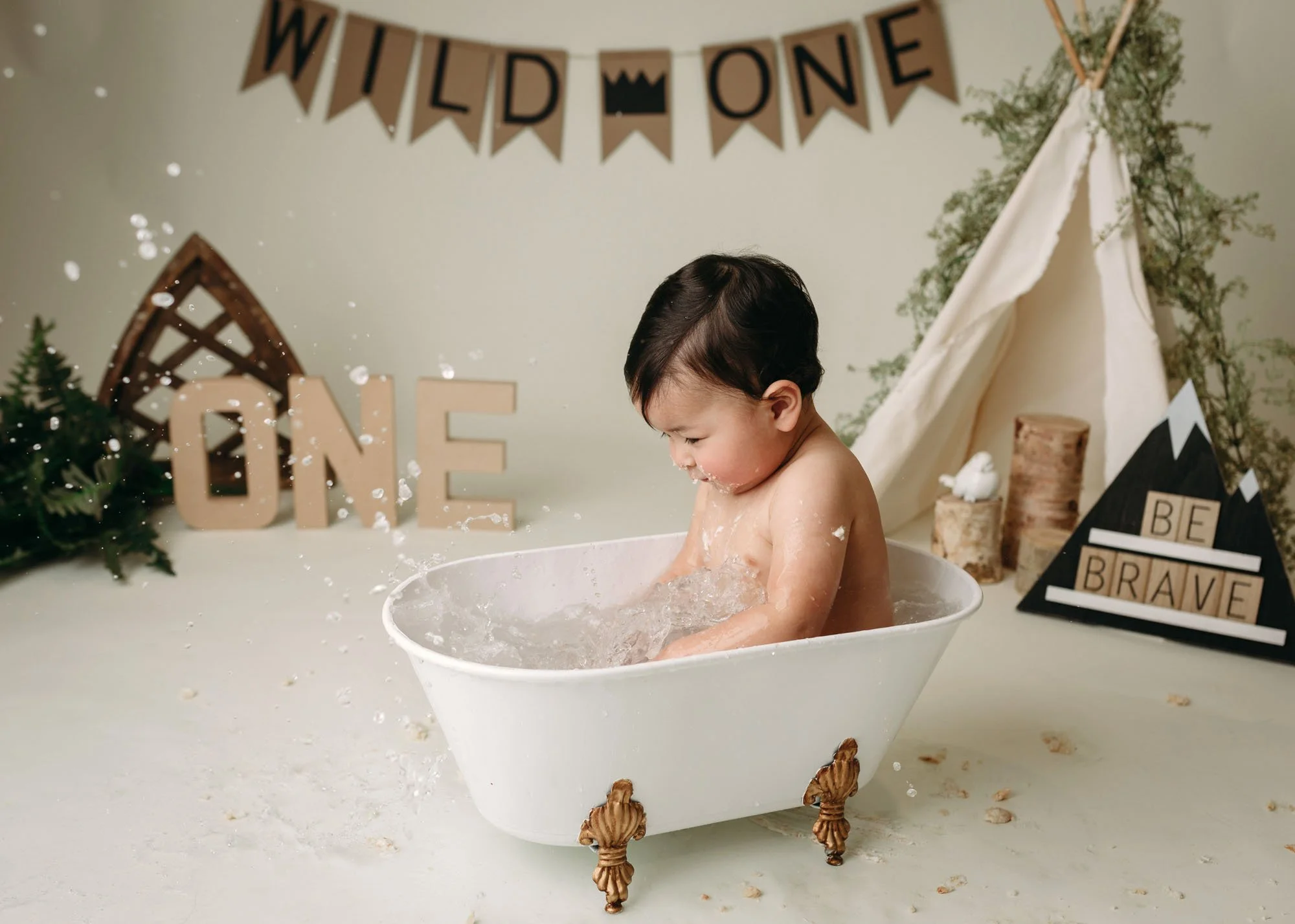 Baby boy celebrating first birthday in neutral studio setup