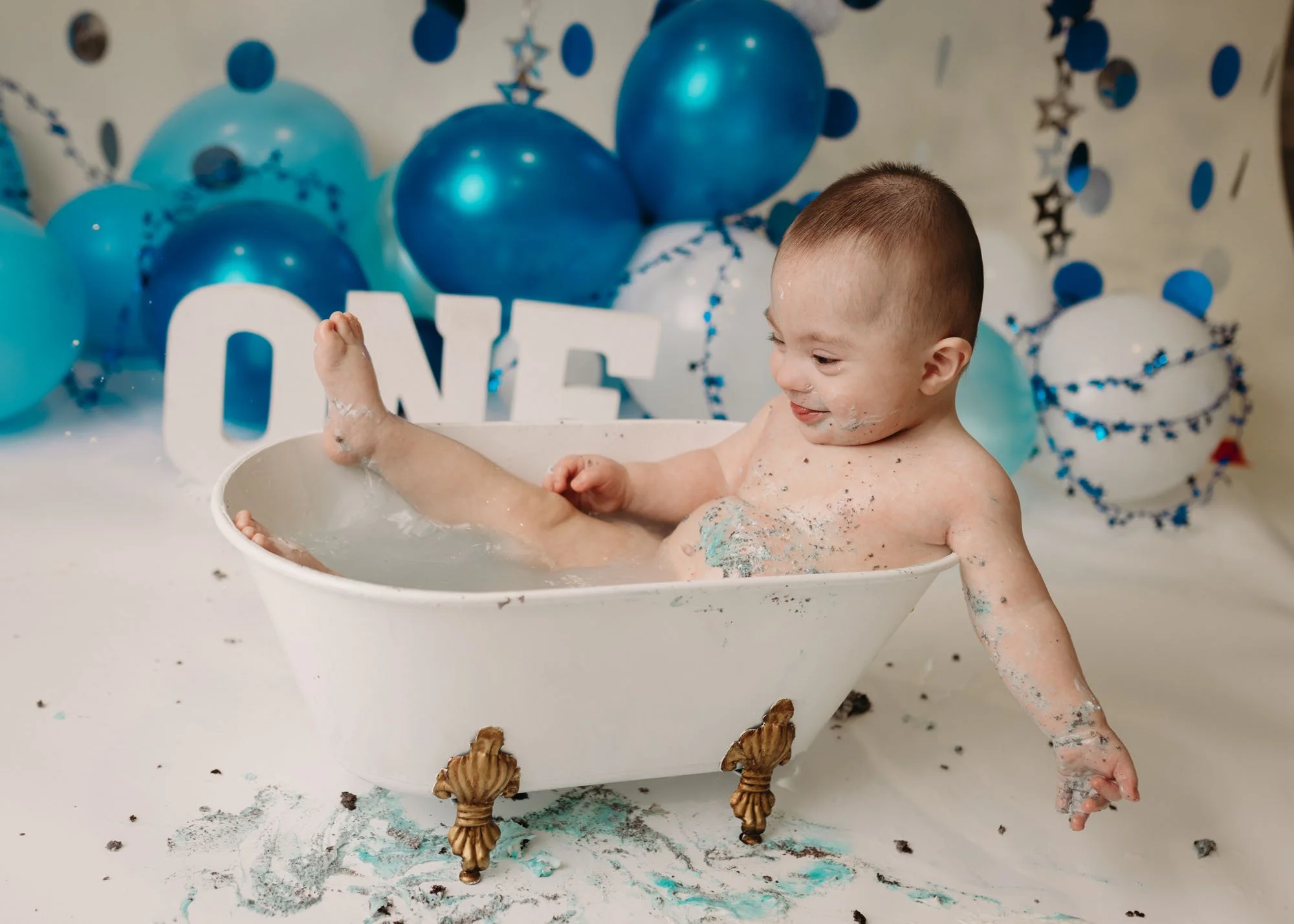 Baby boy enjoying blue themed cake smash in small studio tub