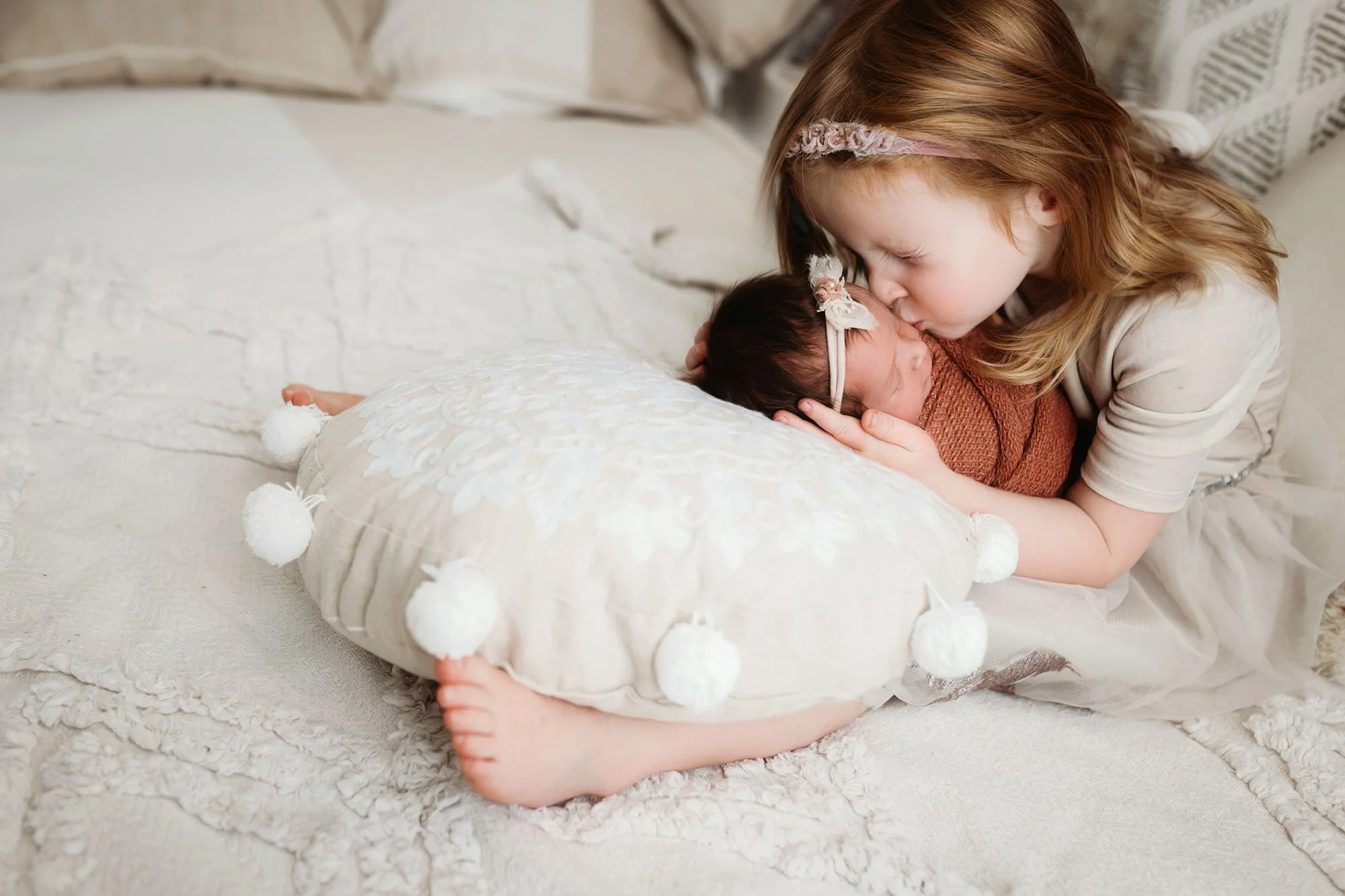 Newborn posed on tummy in miniature bed with soft neutral styling