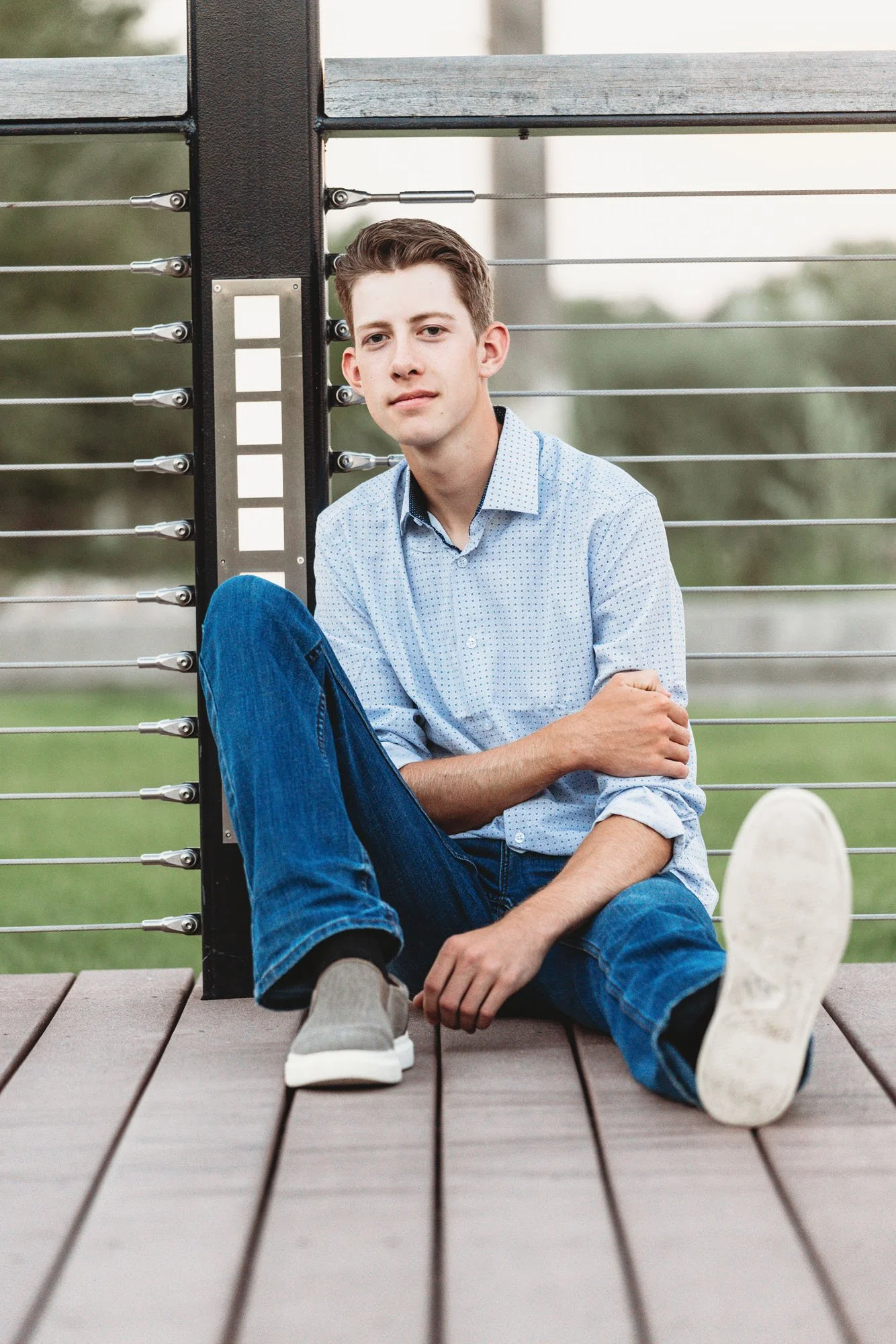 Senior boy leaning against fence for outdoor portrait session