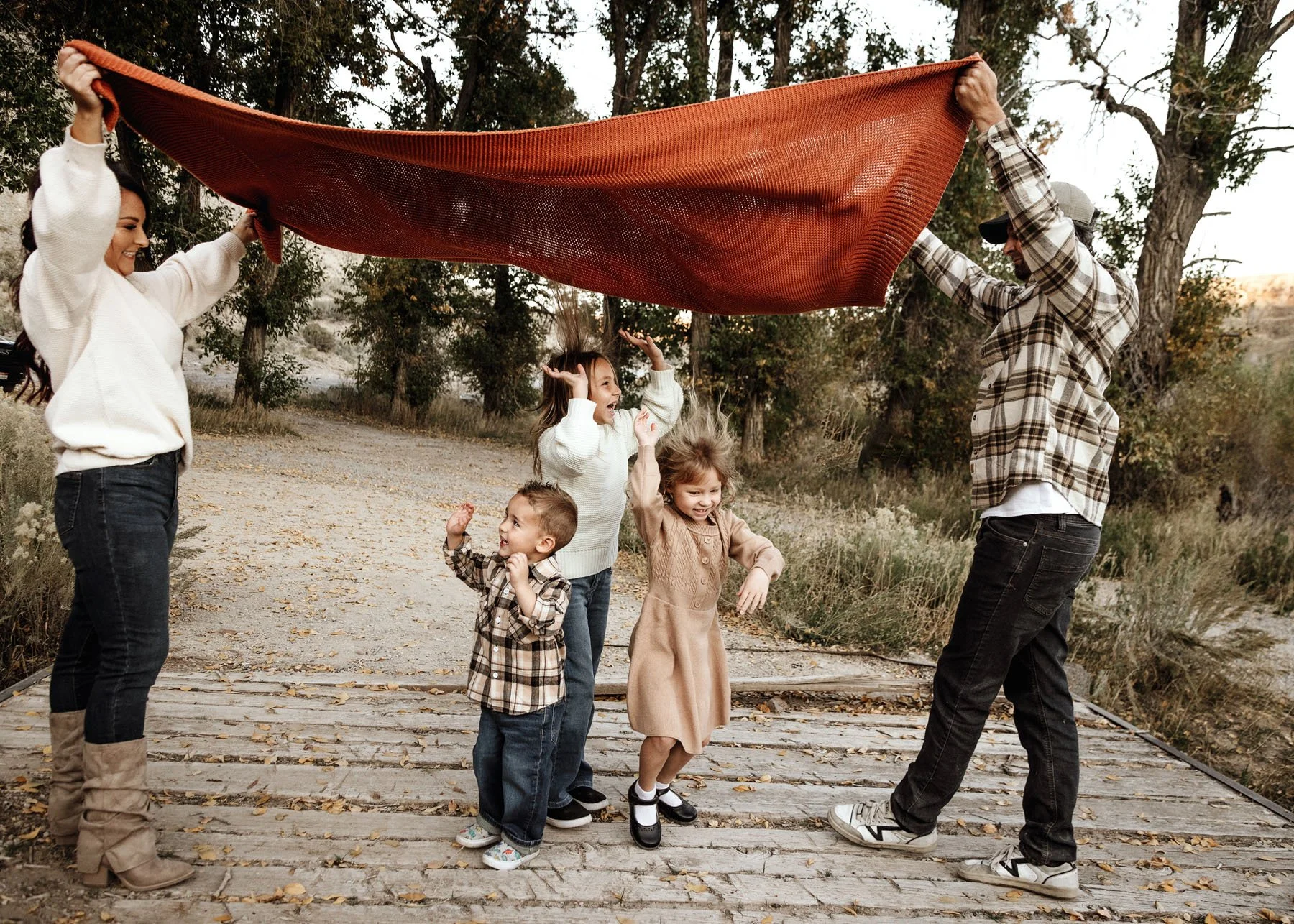 Children playing games under blanket with family smiling