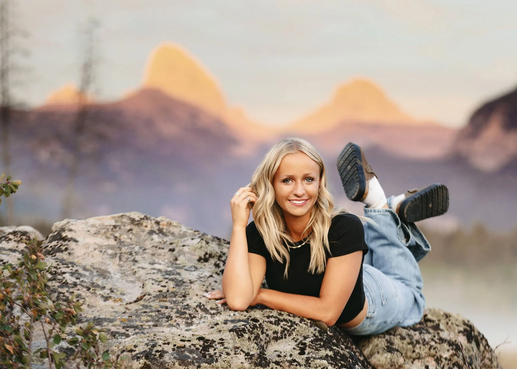 Senior girl laying on rock with Grand Teton mountains behind