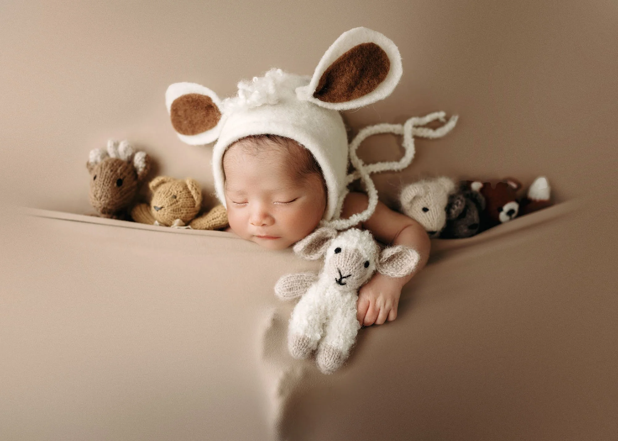 all tucked in newborn with his stuffie friends