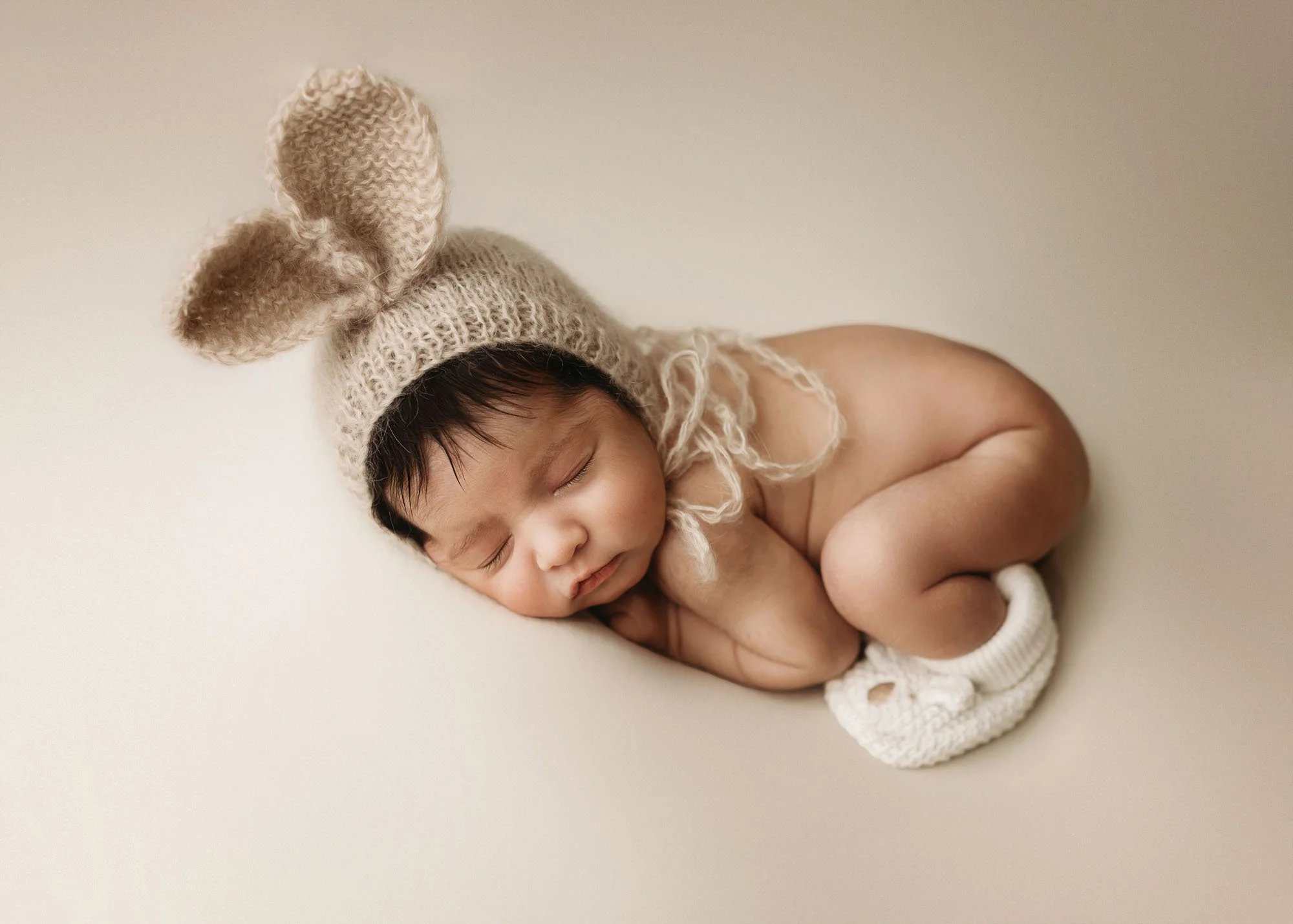 Newborn in neutral bum up pose wearing knit hat in Idaho Falls studio