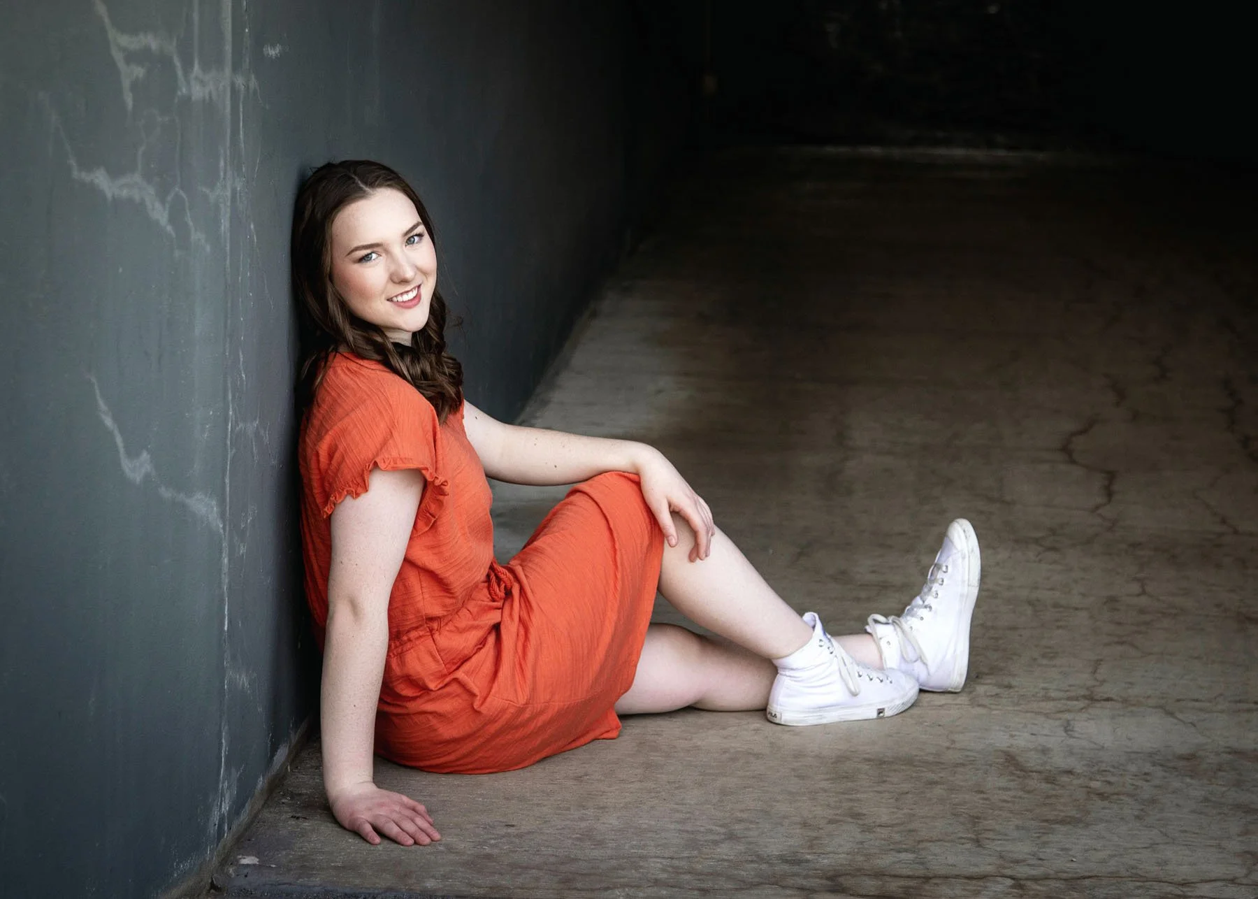 Senior girl leaning against tunnel wall for dramatic outdoor portrait
