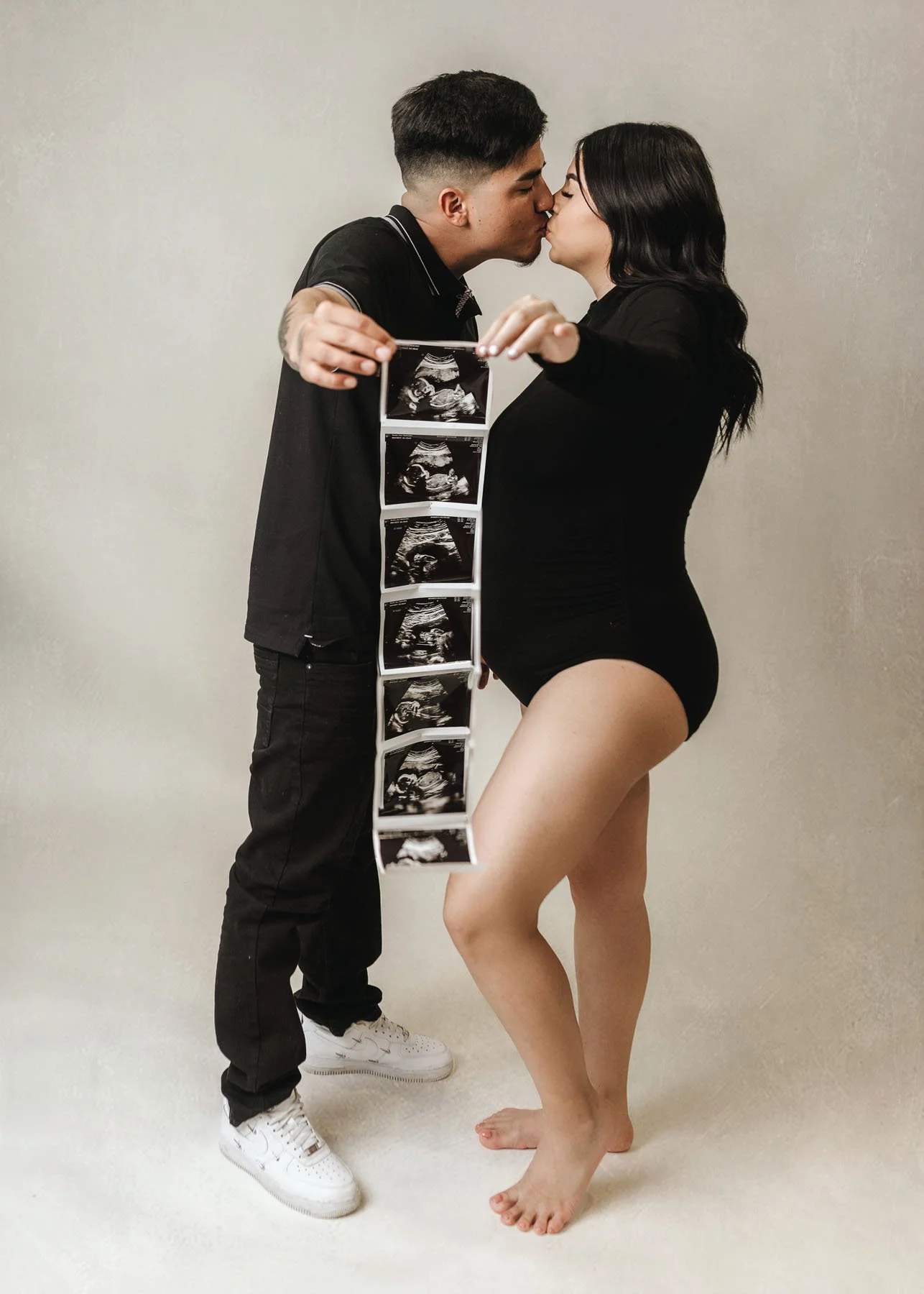 Couple kissing holding ultrasound picture towards camera